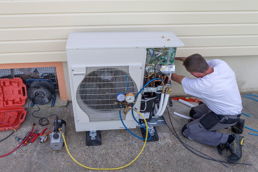 un technicien qui installe une thermopompe extérieur