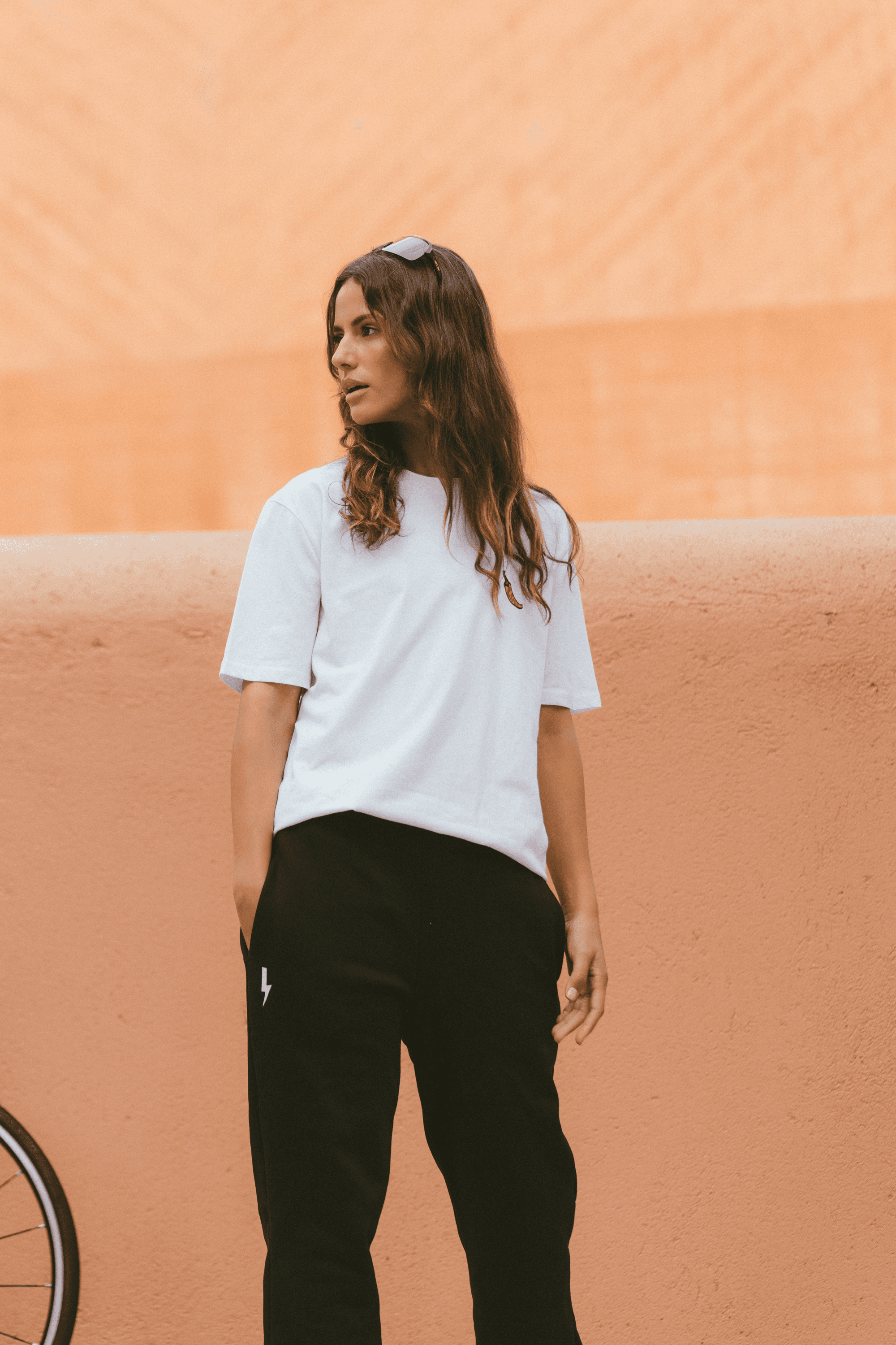 Woman-wearing-a-relaxed-white-t-shirt-and-blacktracksuit-bottoms-with-a-white-lighting-bolt-sign