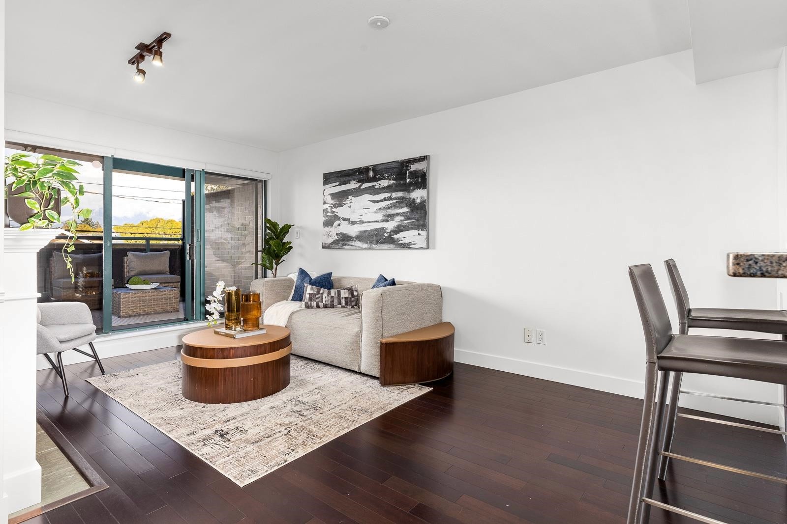 Light-filled modern living room with a cozy sofa, coffee table, and dining area, featuring large windows.