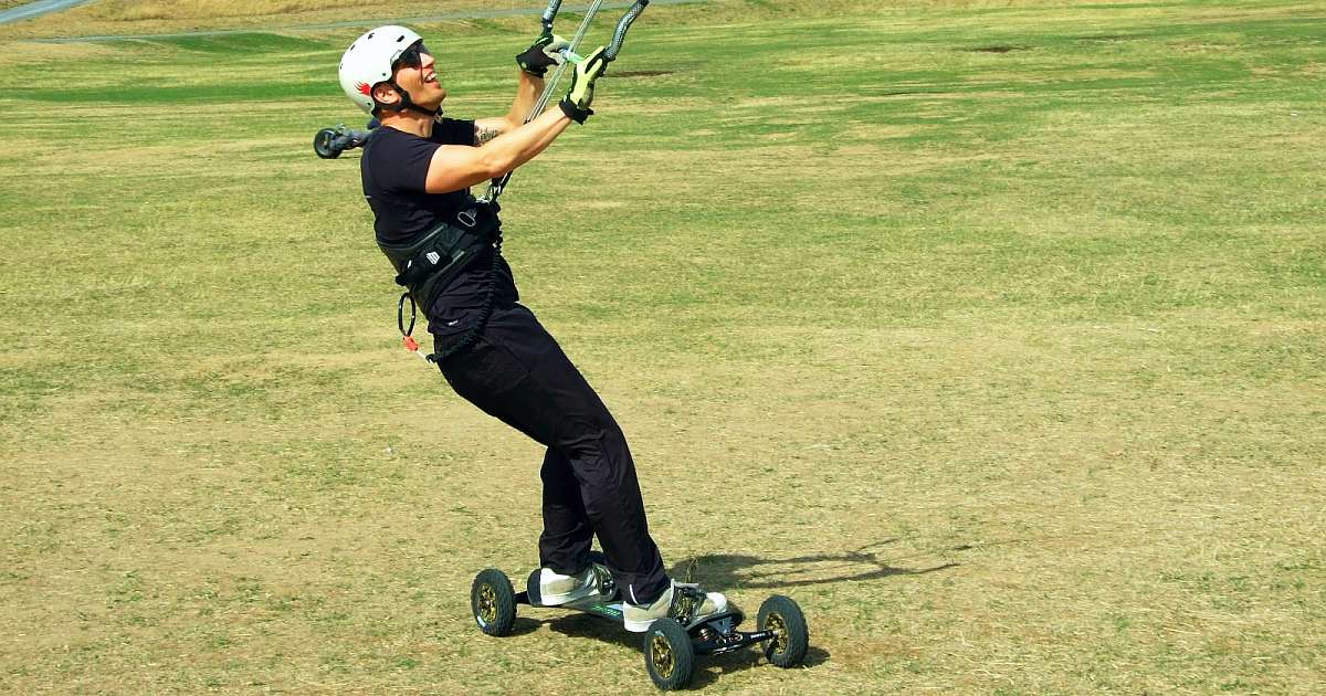 Ein Mann lässt sich vom Wind auf einem Kiteboard ziehen
