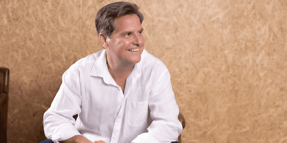 Craig Young smiling in white shirt, founder of Intrinsic Living®, redefining success for high-performing women through emotional mastery.