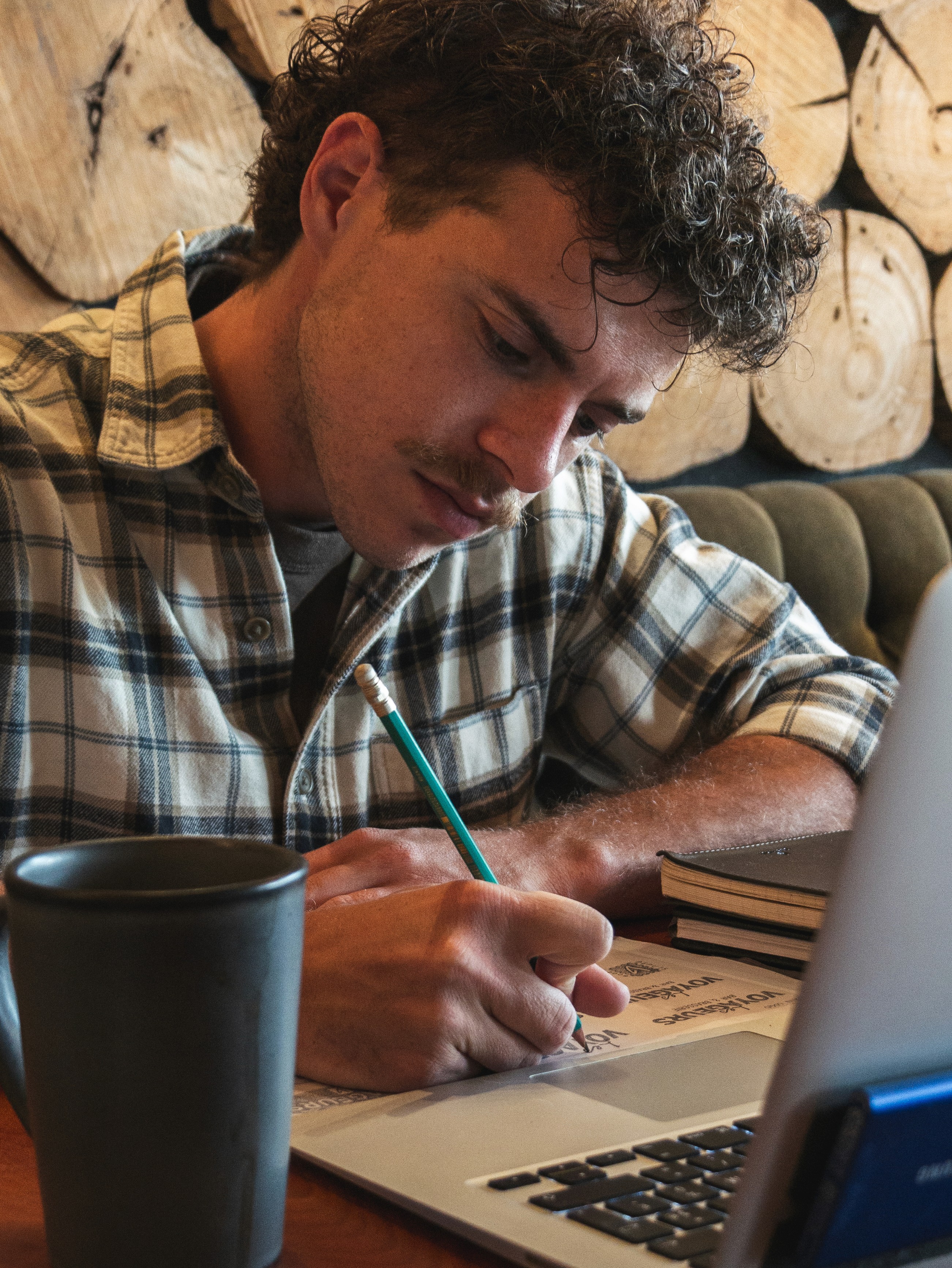 Person wearing a blue puffer jacket and red backpack standing in front of a light blue building on a city street.