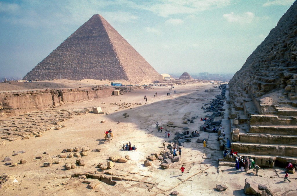 Tourists explore the iconic Pyramids of Giza in Egypt, marveling at the ancient structures and the vast desert landscape, highlighting one of the world's most famous archaeological sites.