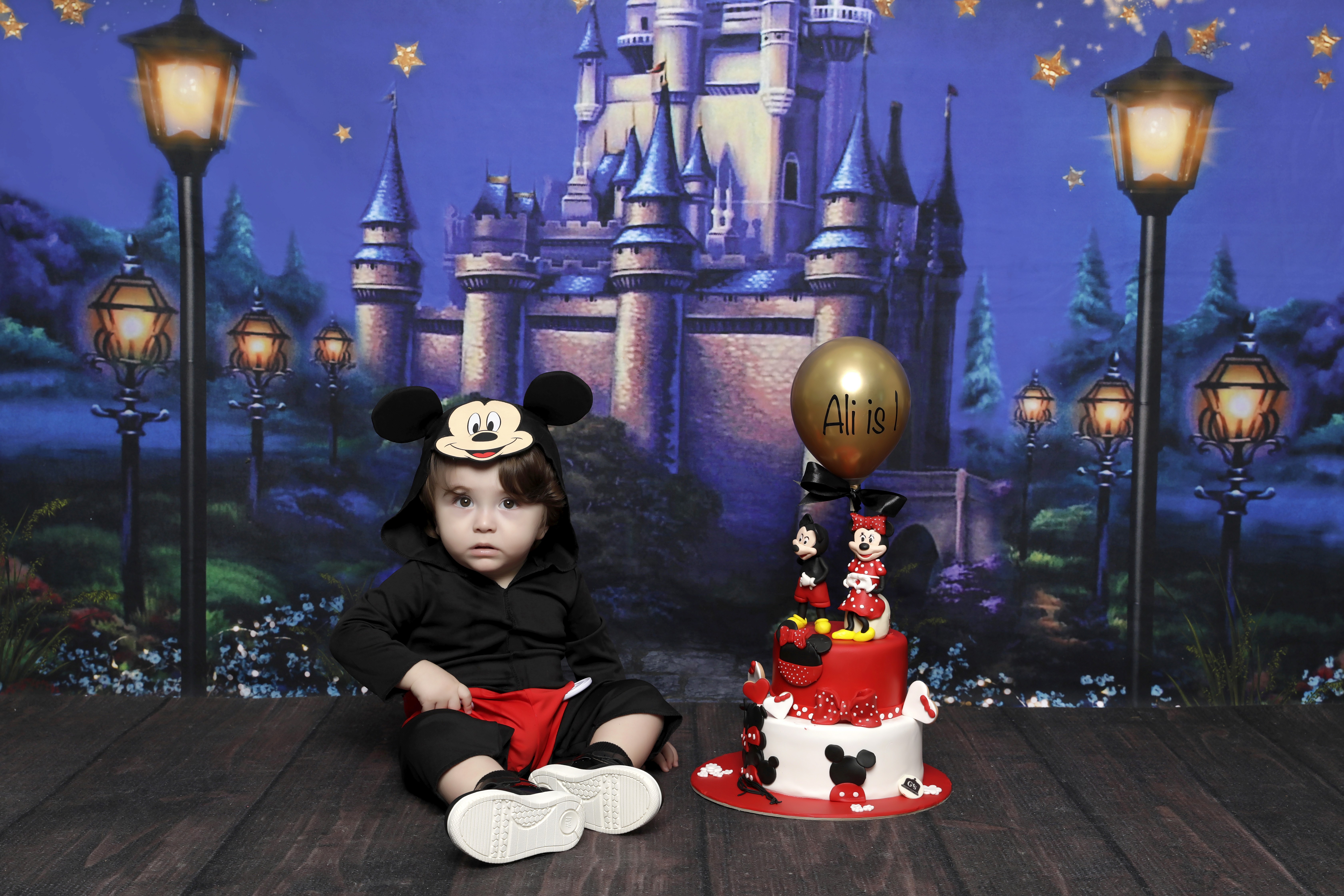 Baby in Mickey outfit with themed birthday cake