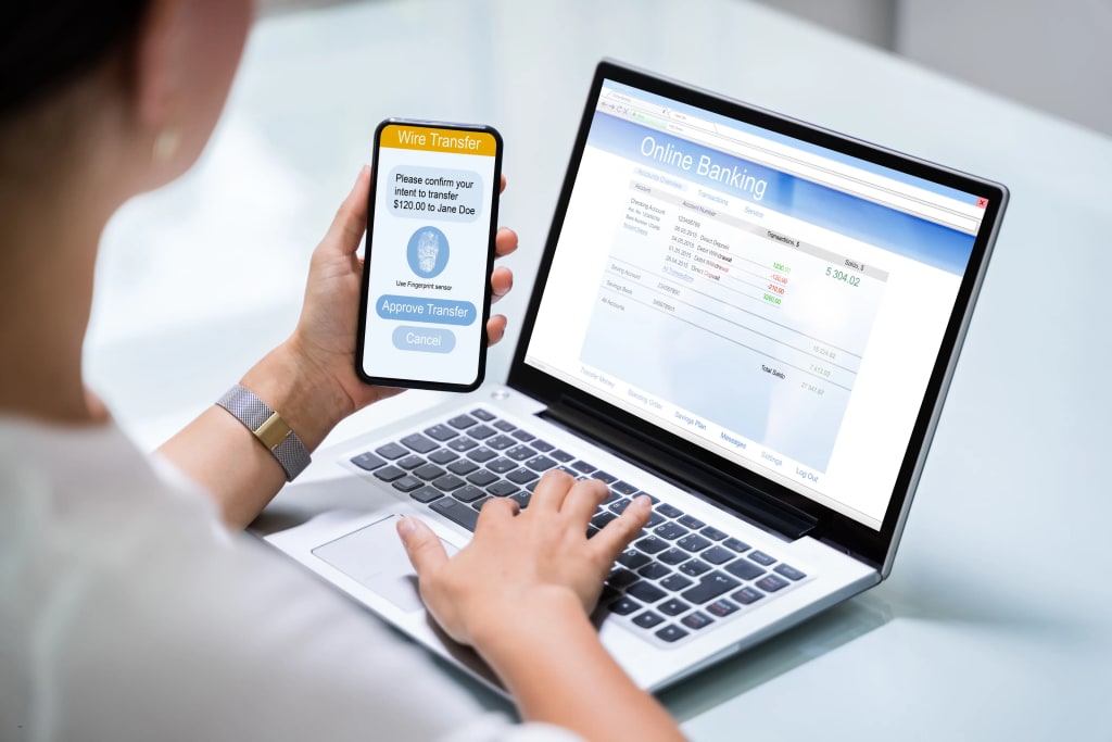 woman using a rent collection app to approve a wire transfer via online banking on laptop and smartphone