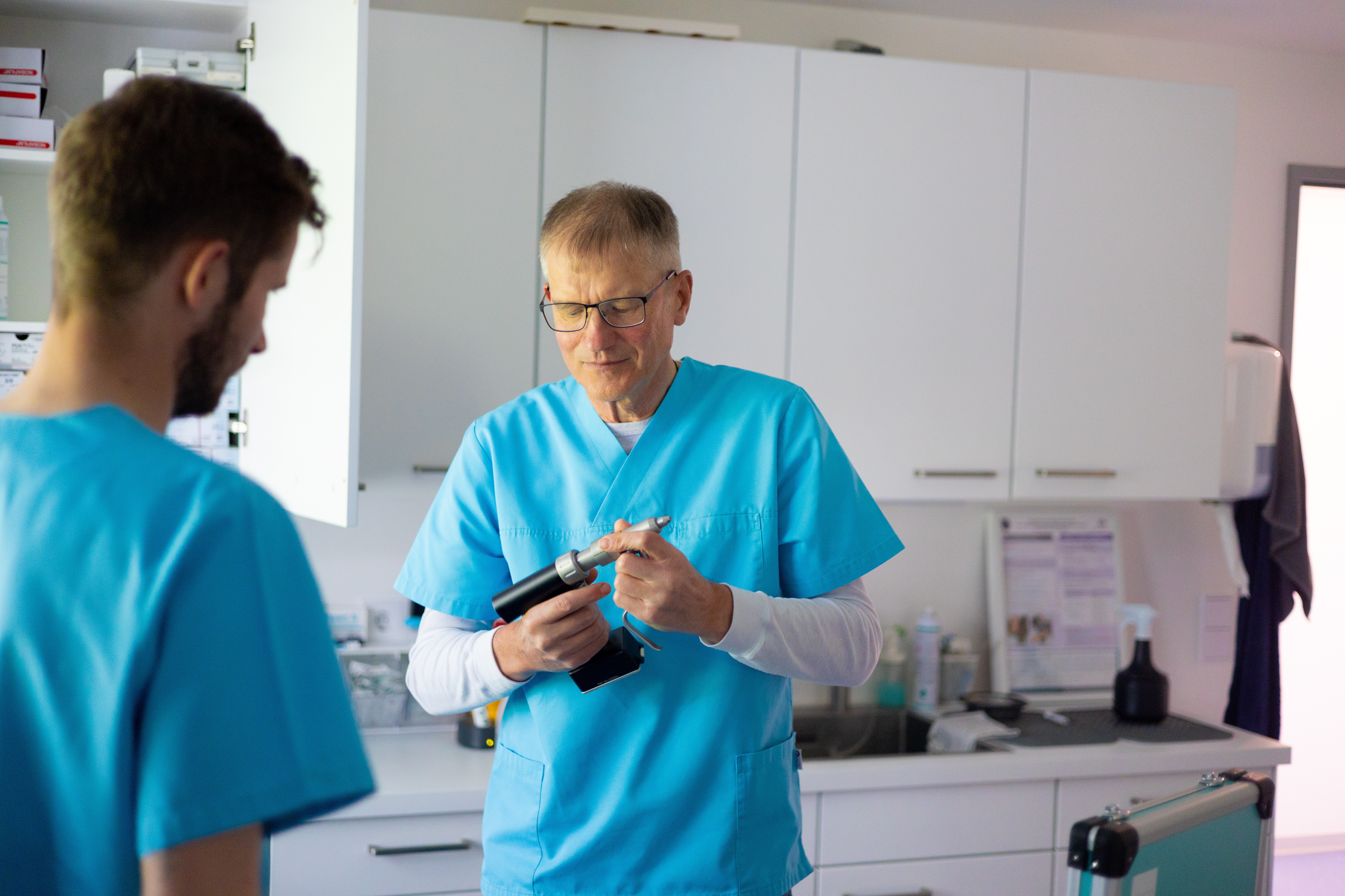 In einer Tierarztpraxis prüft ein Tierarzt mit Brille ein Instrument