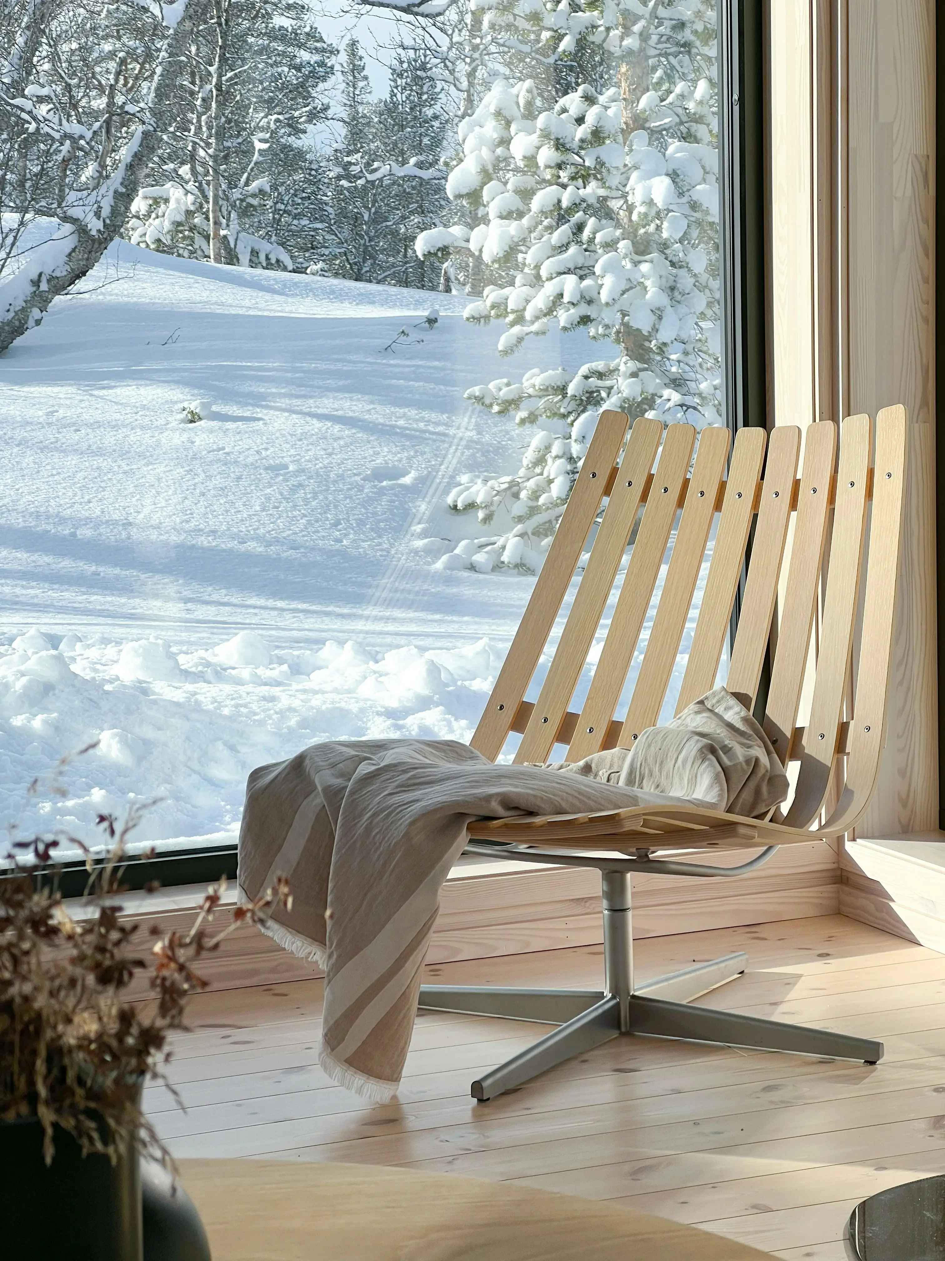 A chair positioned near a window, overlooking a snowy landscape.