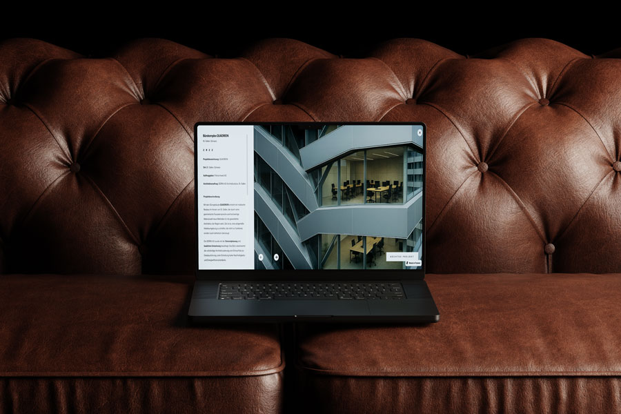 Laptop-Mockup auf braunem Ledersofa mit geöffneter Website von Serra Architektur AG. Auf dem Bildschirm ist das Projekt Quadrion in St. Gallen mit moderner Fassadenansicht und Projektbeschreibung zu sehen.