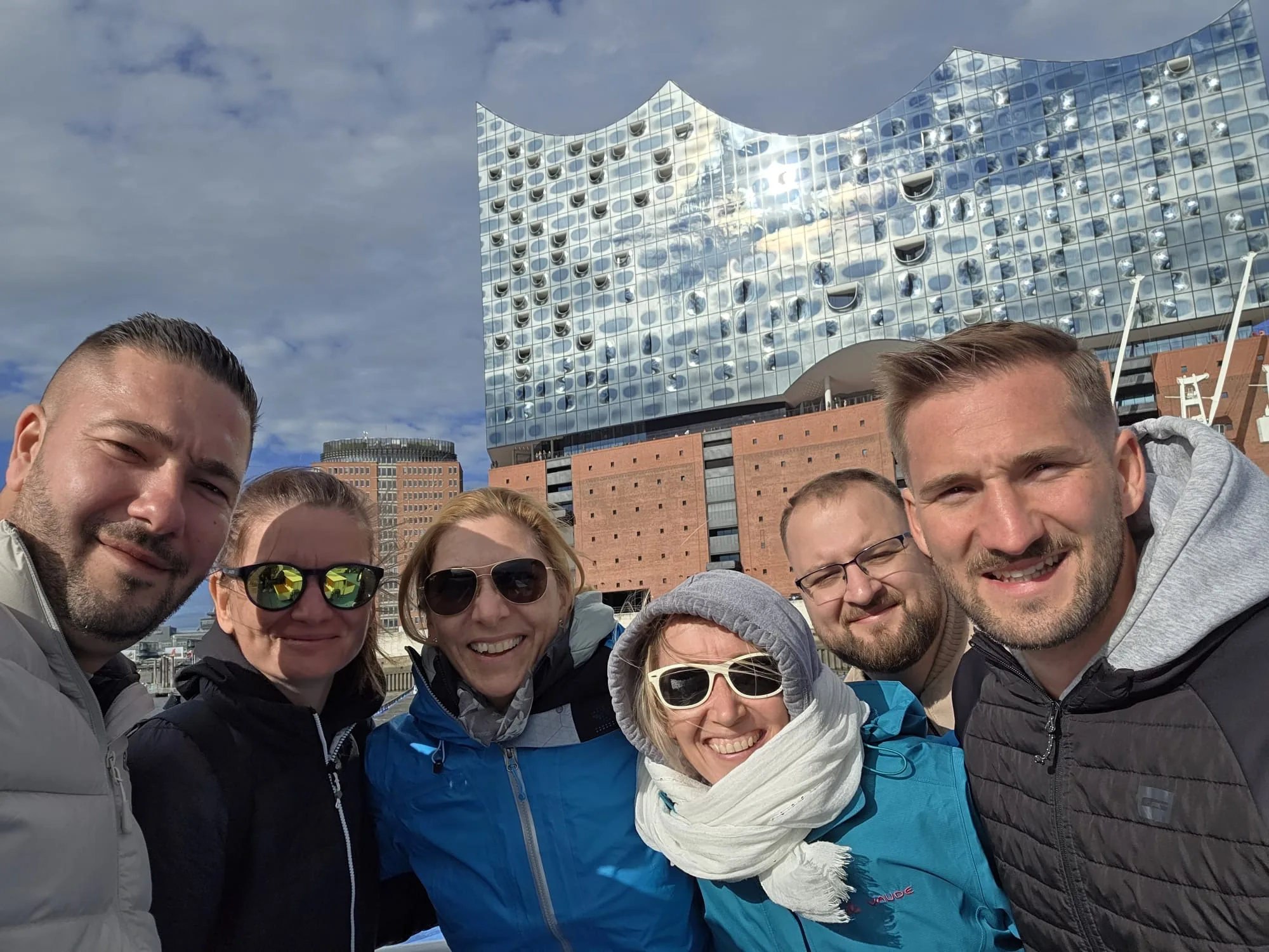 Sechs Teammitglieder machen ein Selfie vor der Elbphilharmonie in Hamburg