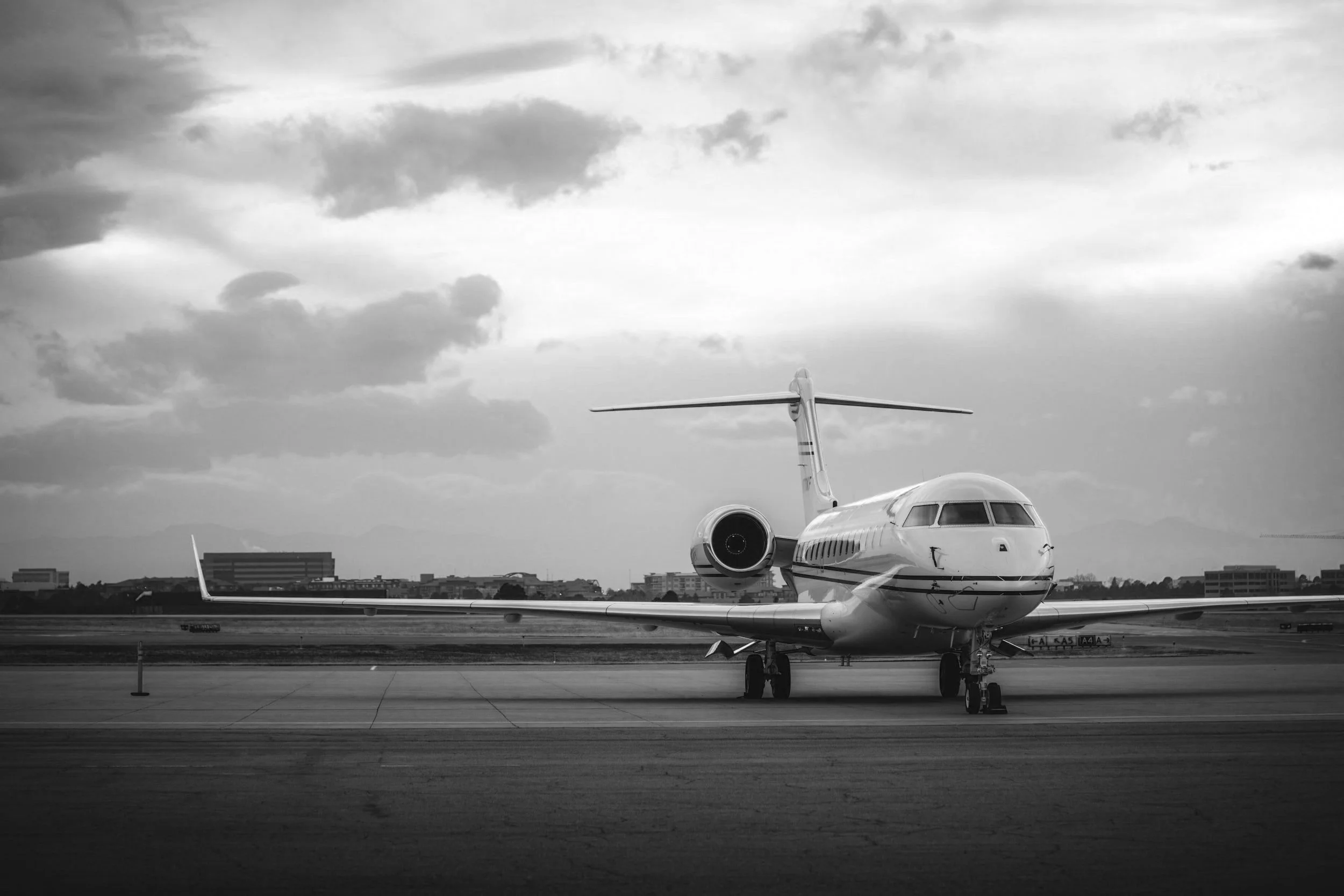 Private jet on an airport runway under a cloudy sky