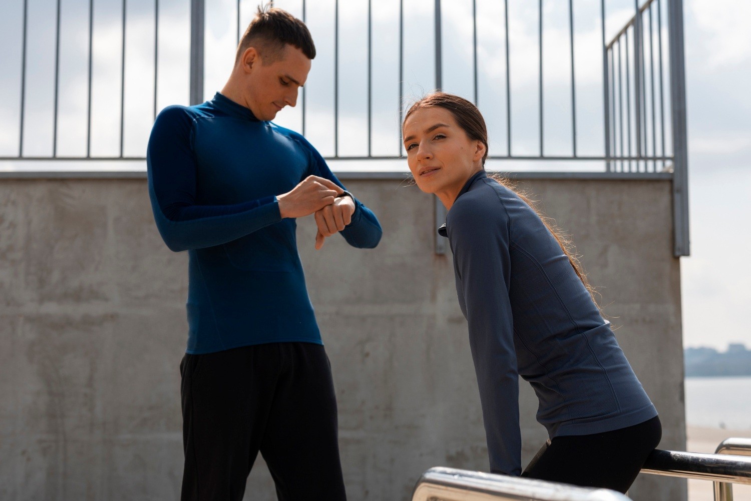 Dwójka biegaczy sprawdzająca dane treningowe na smartwatchu przed biegiem