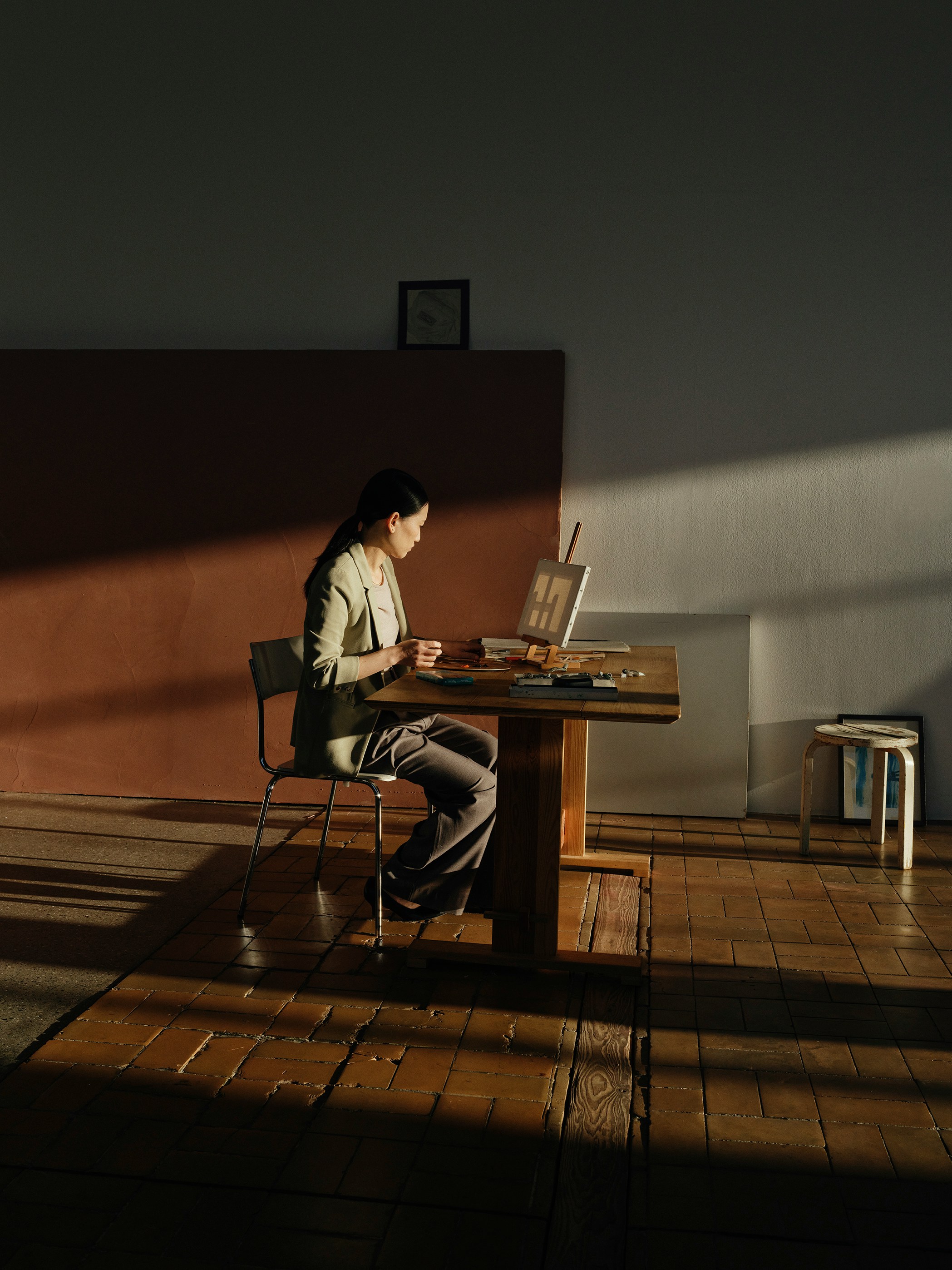 Woman painting at a wooden table in sunlight
