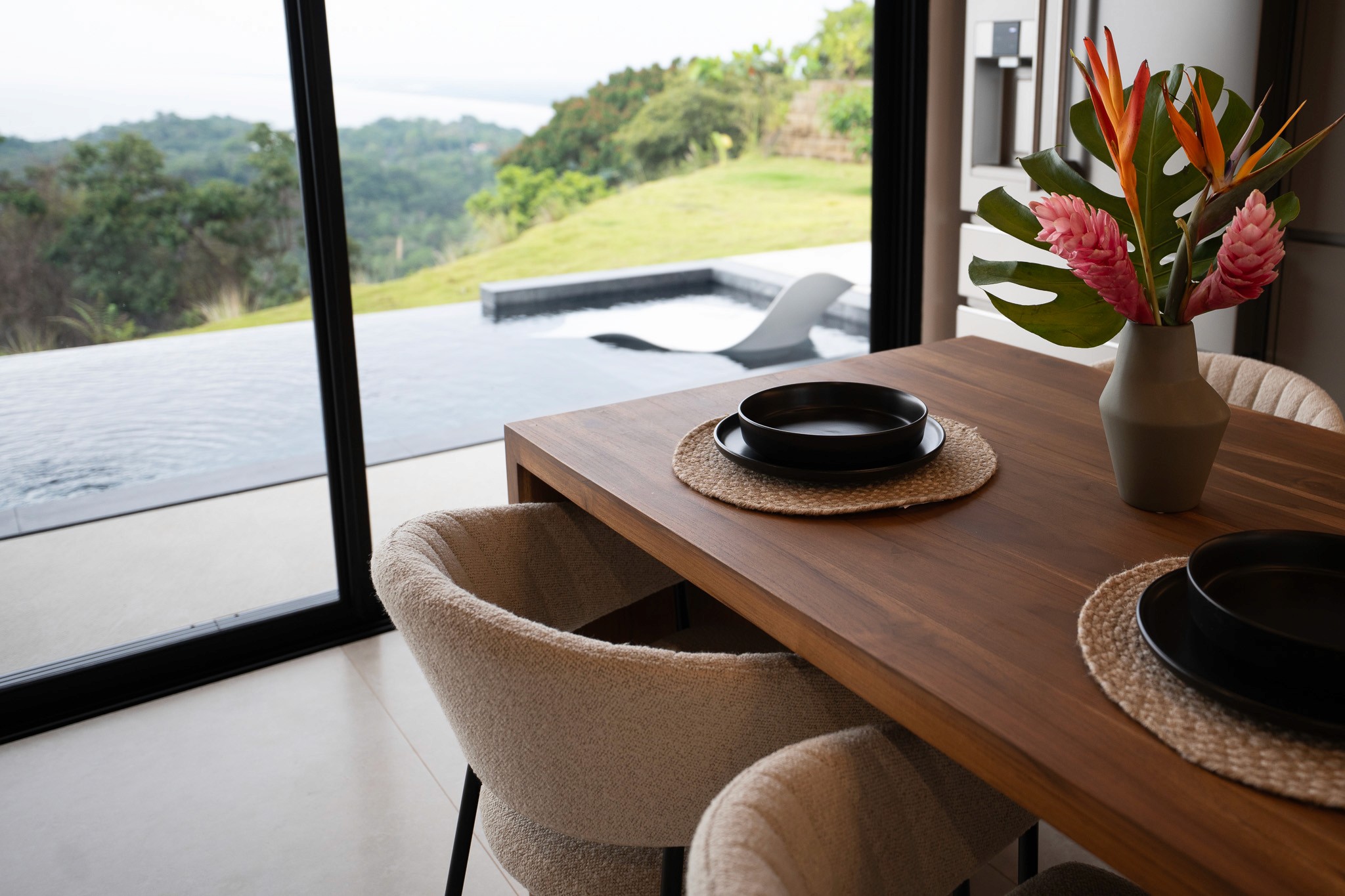 nfinity pool blending into the ocean view, minimalist sun loungers in soft neutral fabric, curved architecture