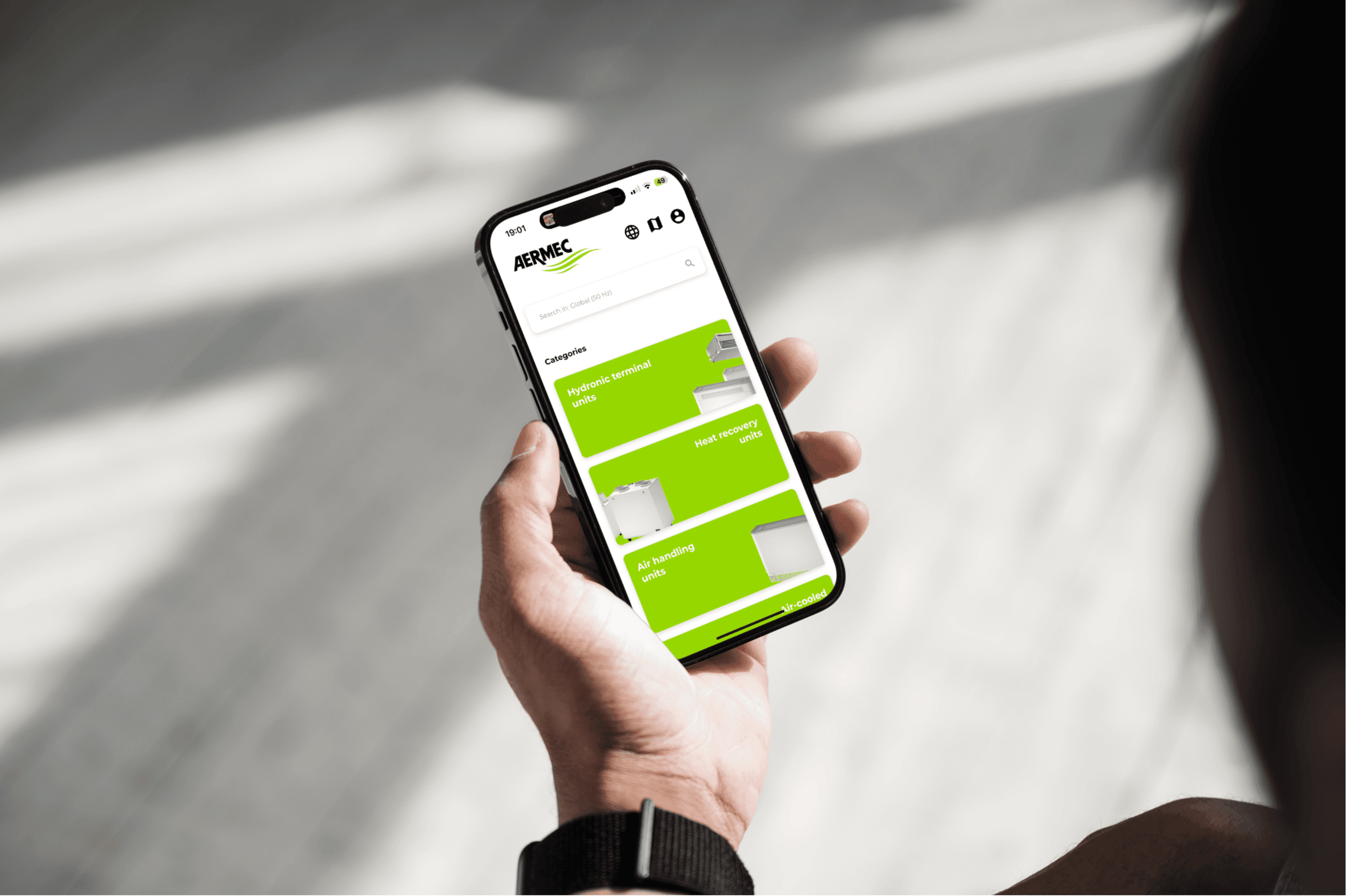 Hand met smartphone toont de AERMEC-website met productcategorieen