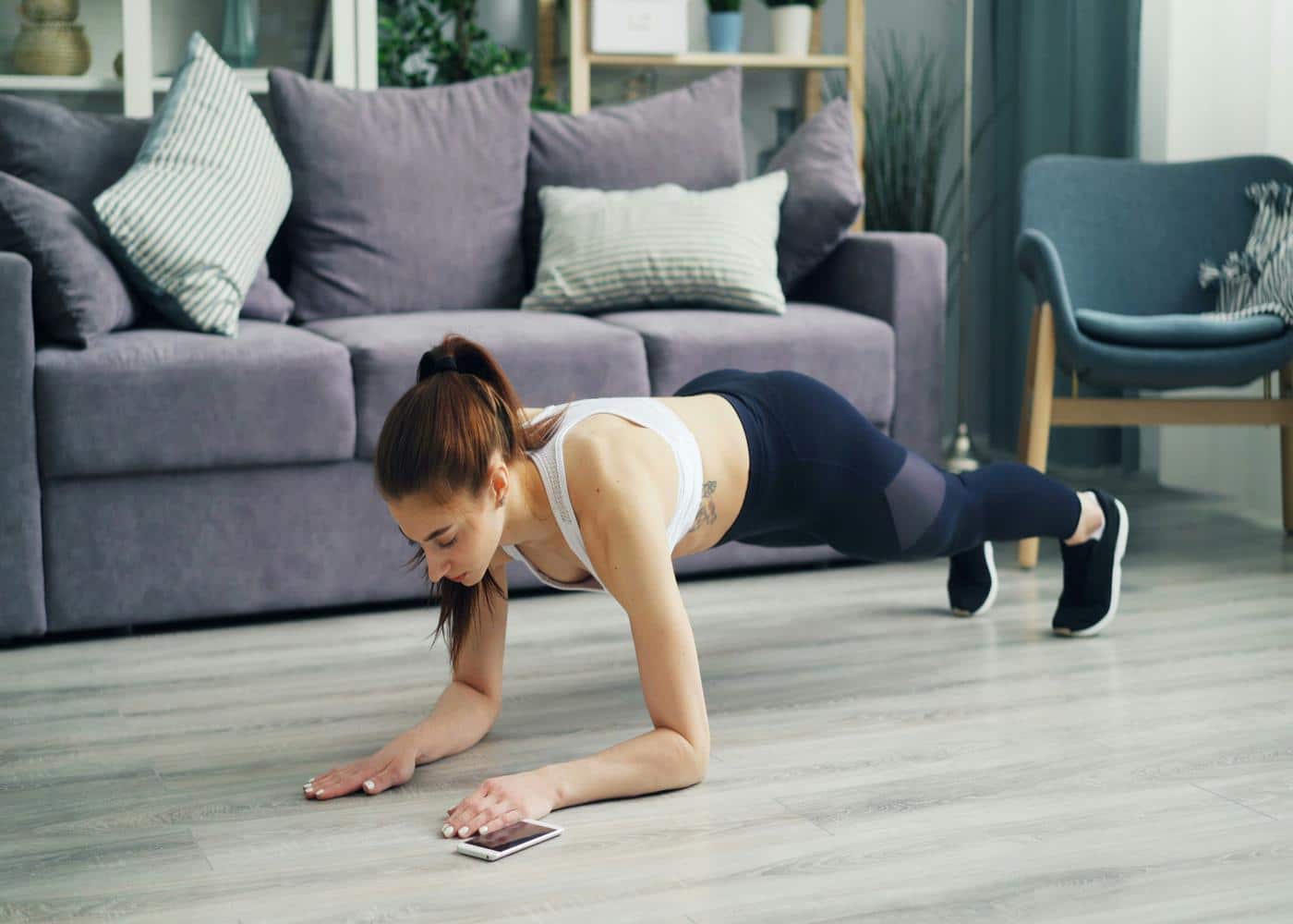Woman strength training at home in front of a couch