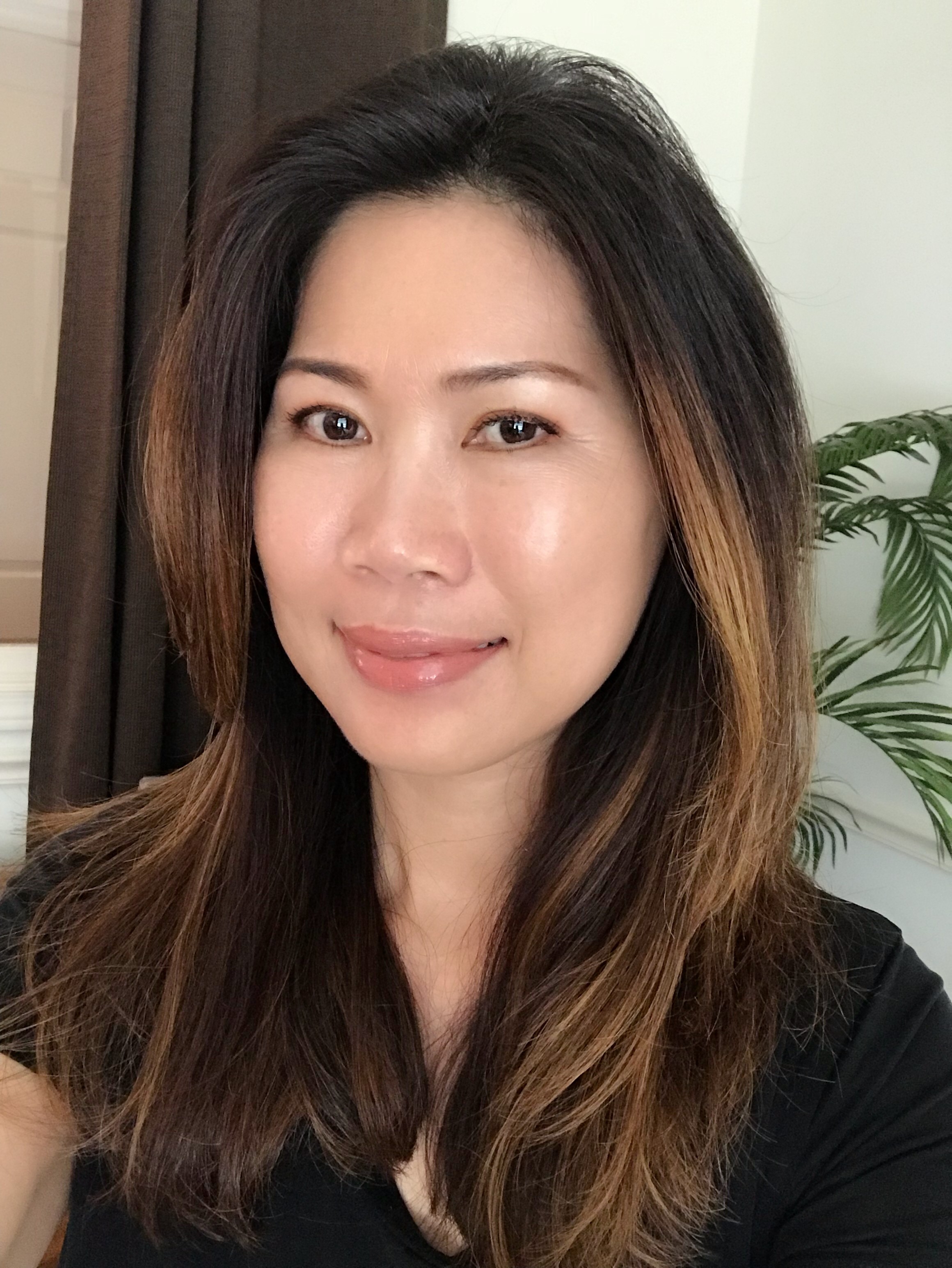 Portrait of a woman with long red hair and closed eyes, gently touching her face with both hands