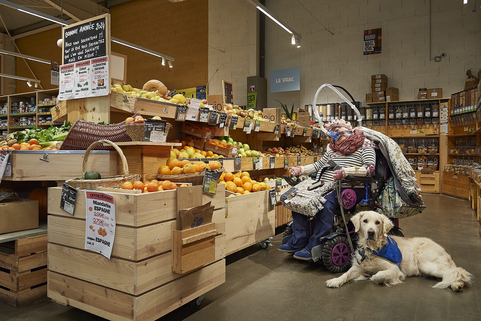 Marie accompagnée de son chien d’assistance Mader, photographiés par Frédéric Bourcier dans le cadre d’un reportage documentaire social pour Handi’Chiens au Biocoop de Chatte Saint-Marcellin.