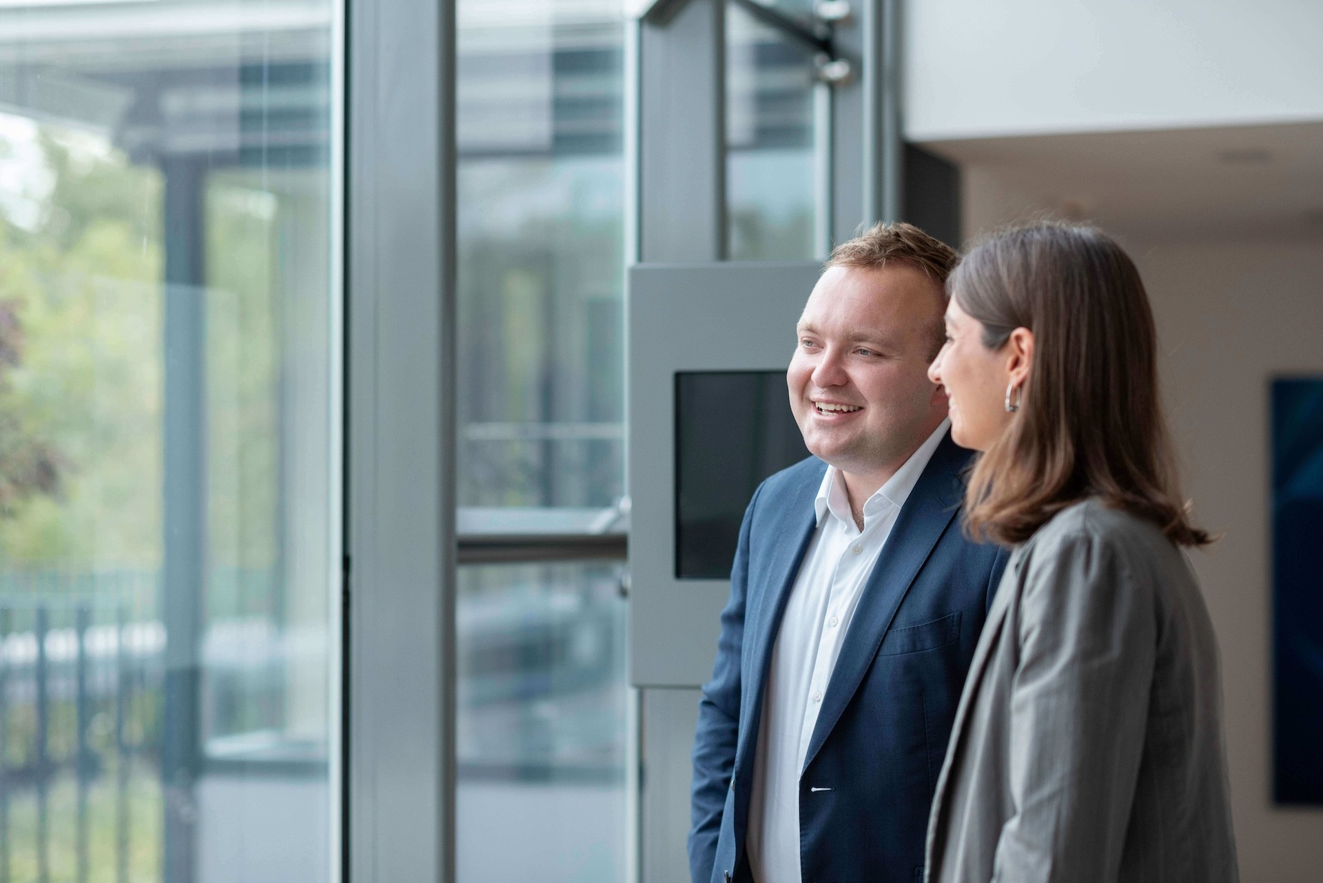 Two Team colleagues happily sharing a conversation by a window 