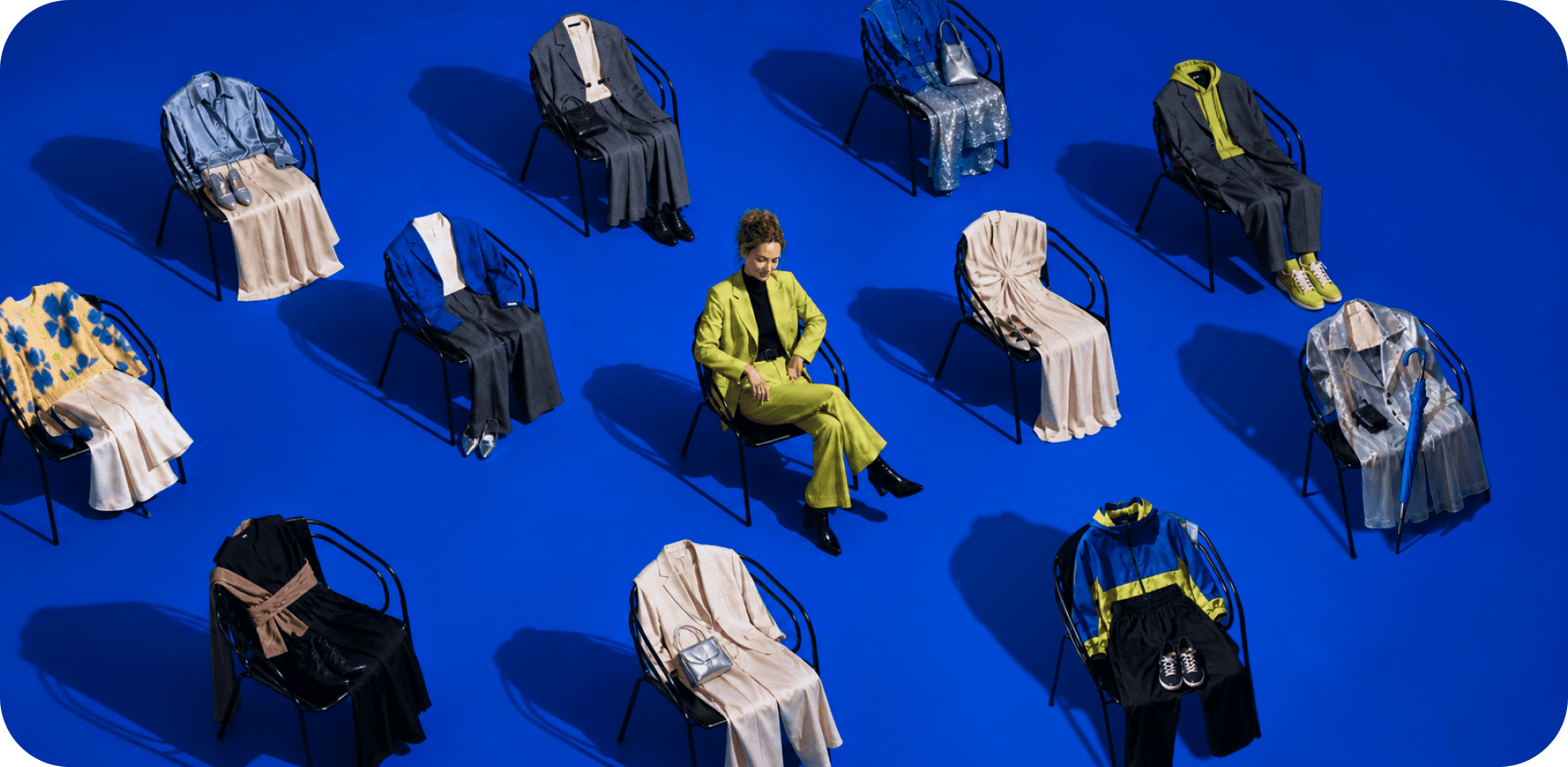 woman in a lime suit among chairs draped with different outfits