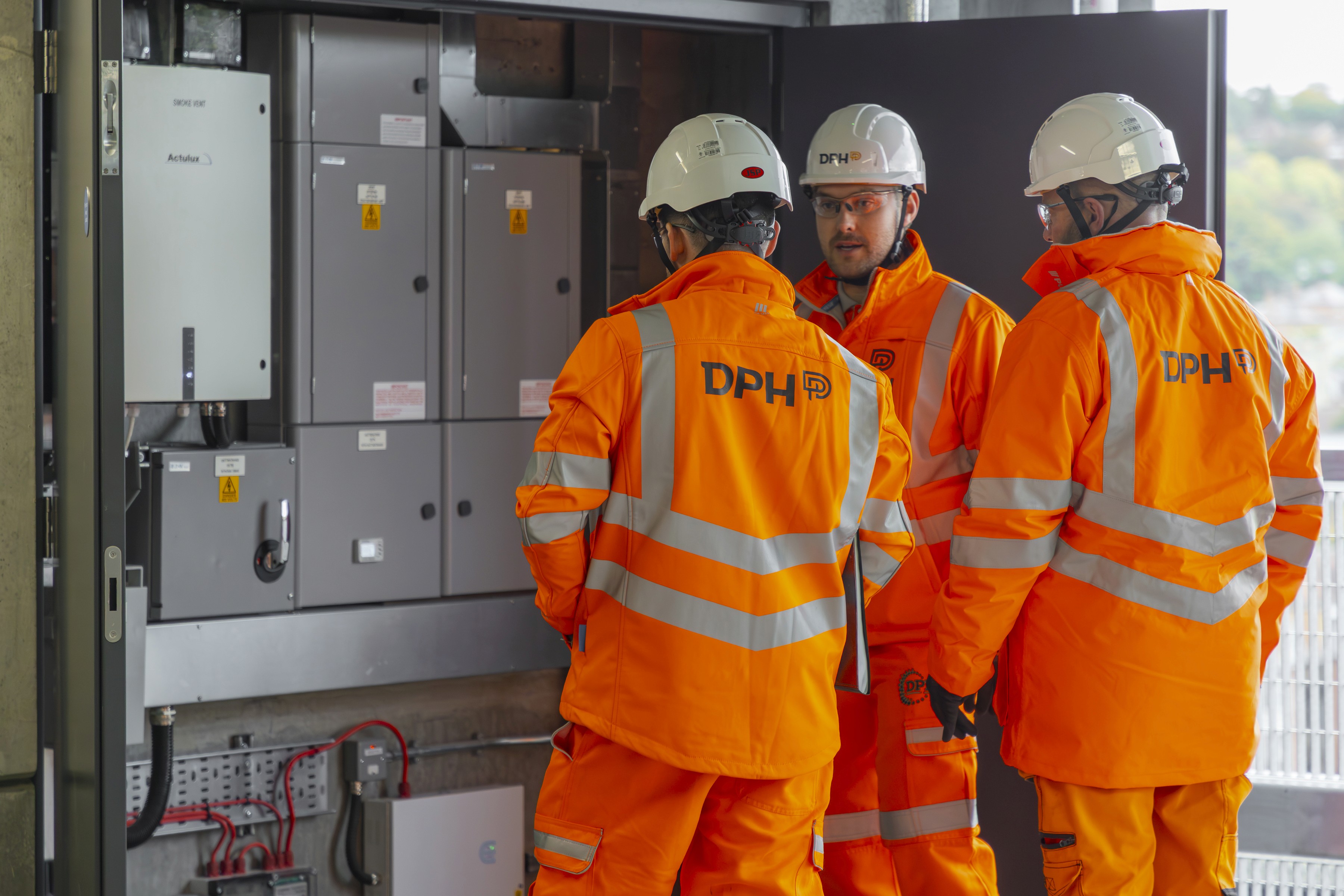 Modern glass building with illuminated interior and reflections at sunset