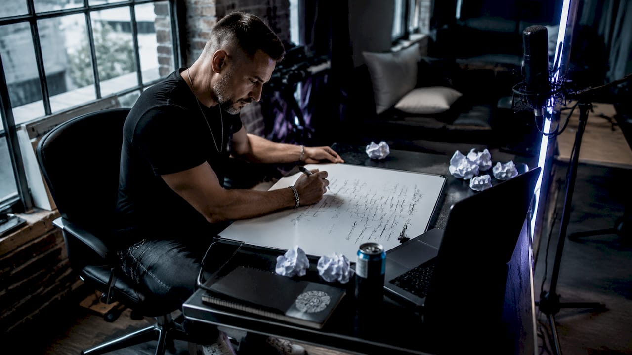 Songwriter writing verses at home desk in warm light