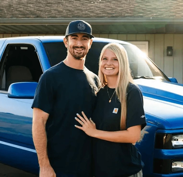 Two people standing in front of a blue truck
