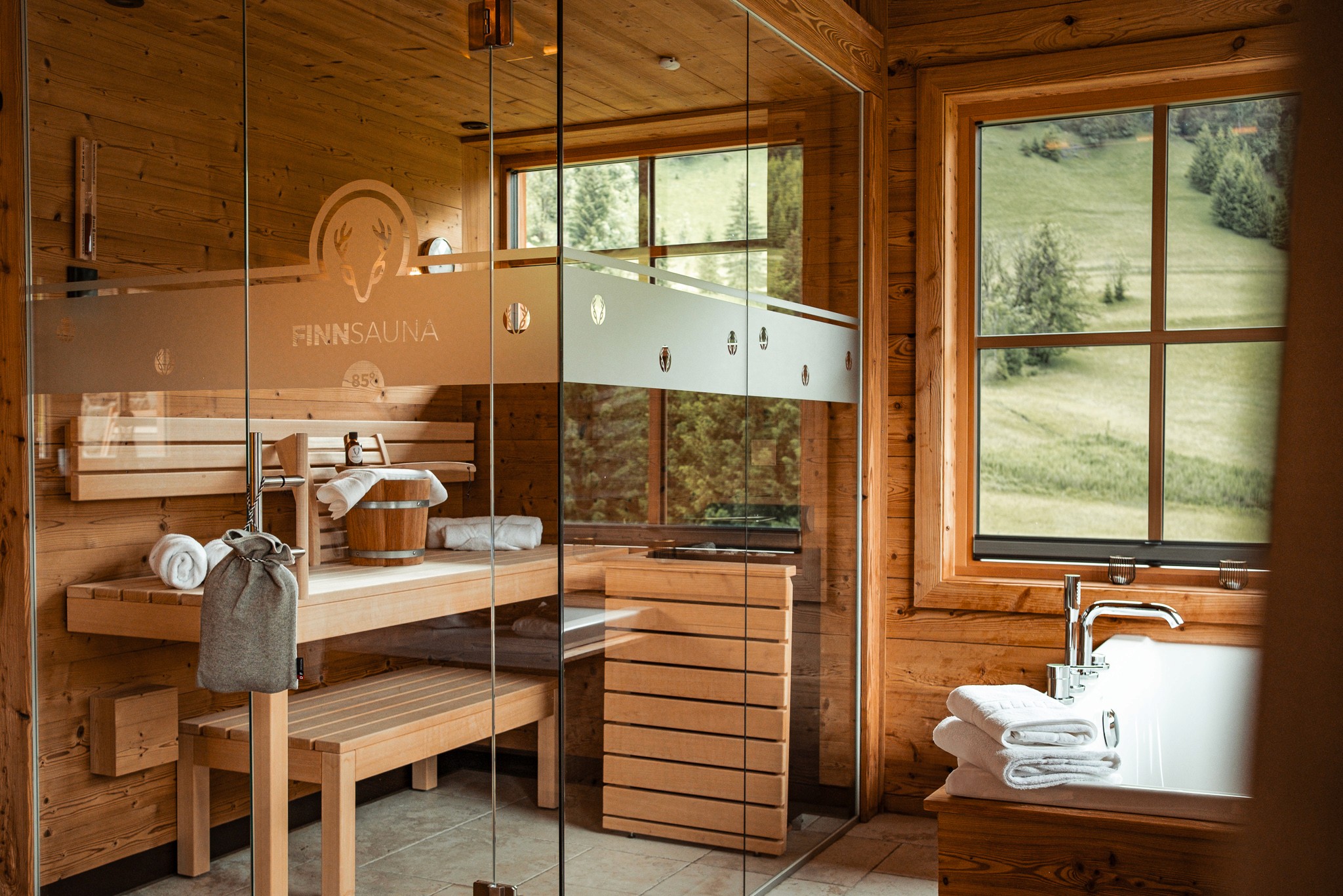 Luxuriöses Badezimmer mit Sauna in einem Chalet mit Panoramafenstern und traditioneller Holzoptik