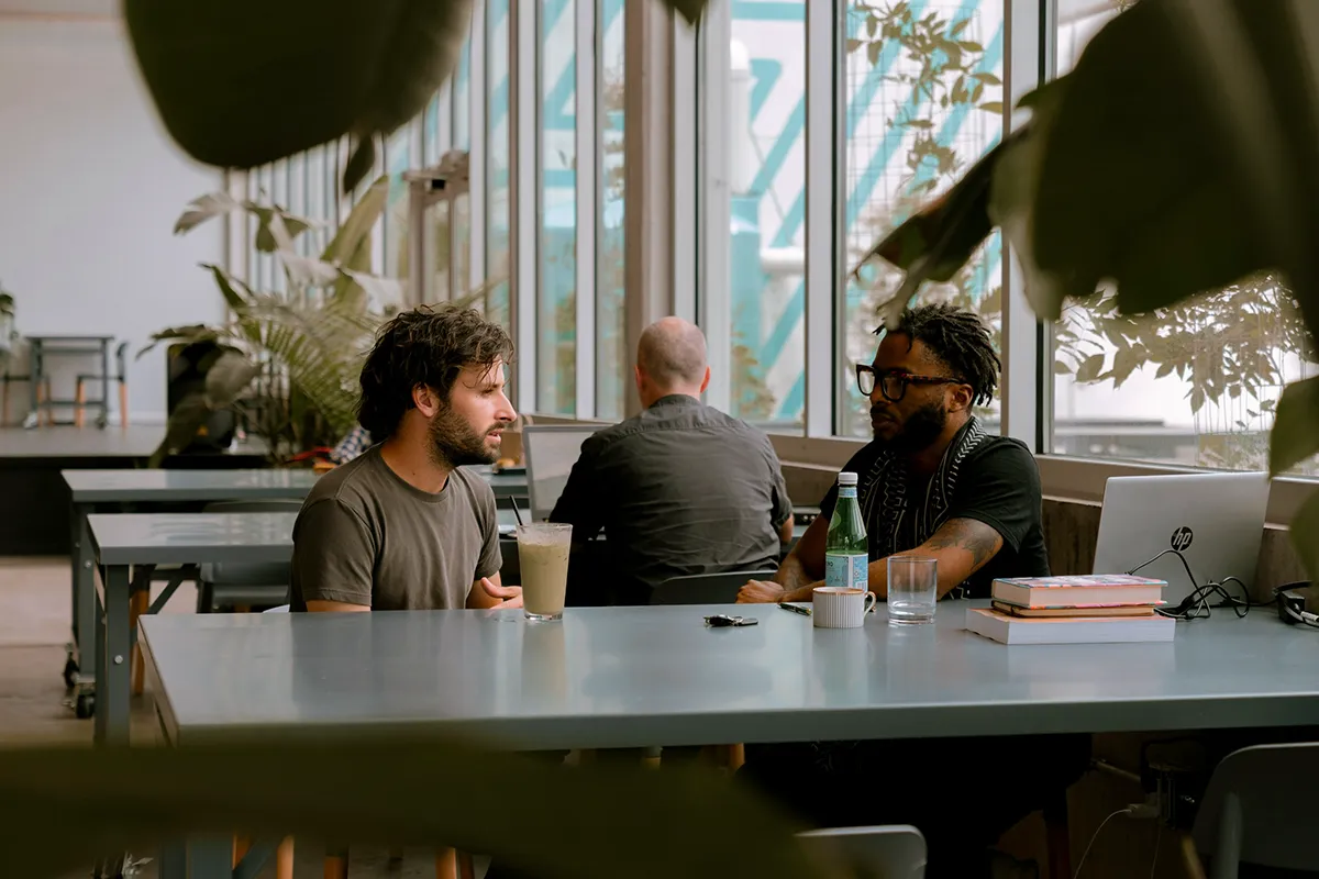 Two men sitting at a laptop deep in conversation at a table