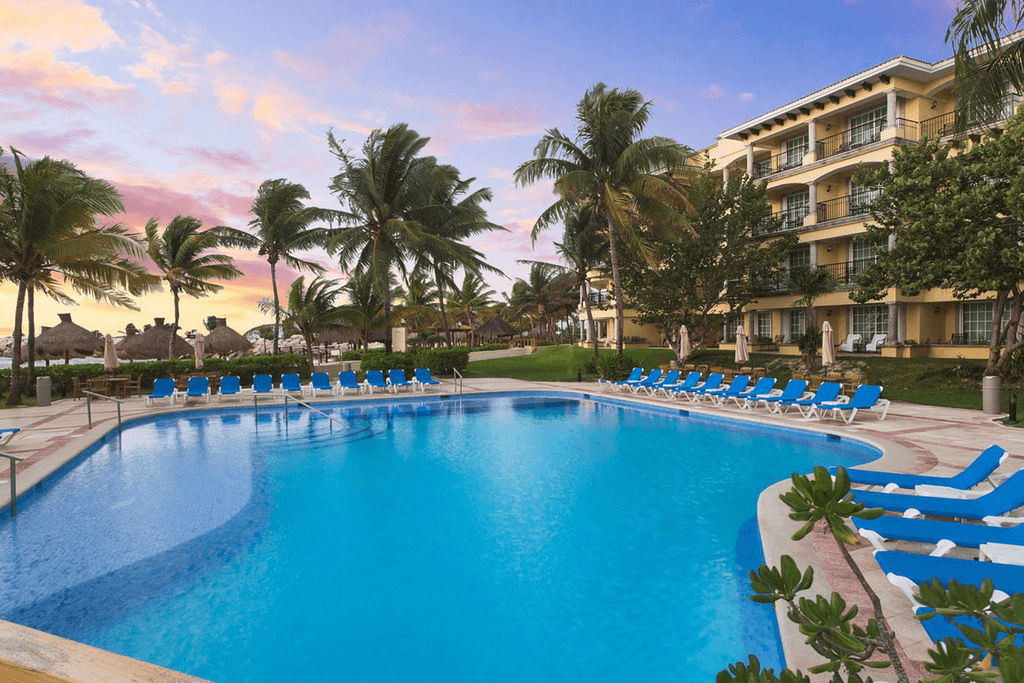 Couple standing on a balcony with binoculars in hand looking out over the ocean