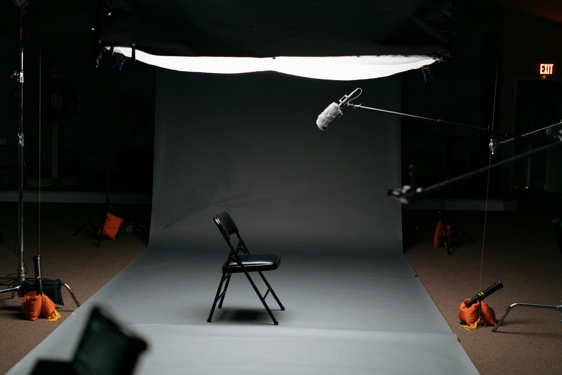 Image of photo studio with a single black fold chair in center frame.