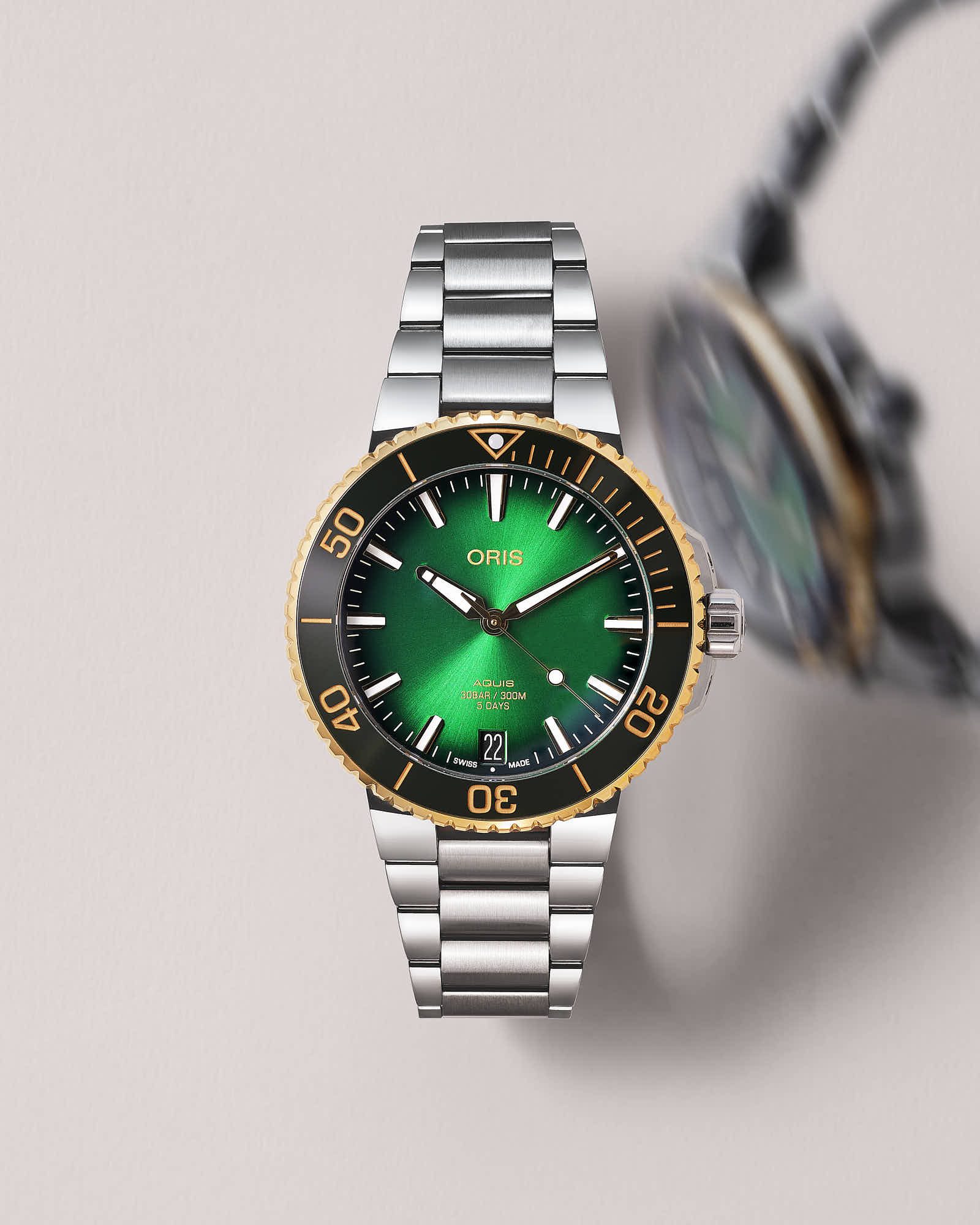 Luxury green dial wristwatch with stainless steel bracelet and gold bezel.