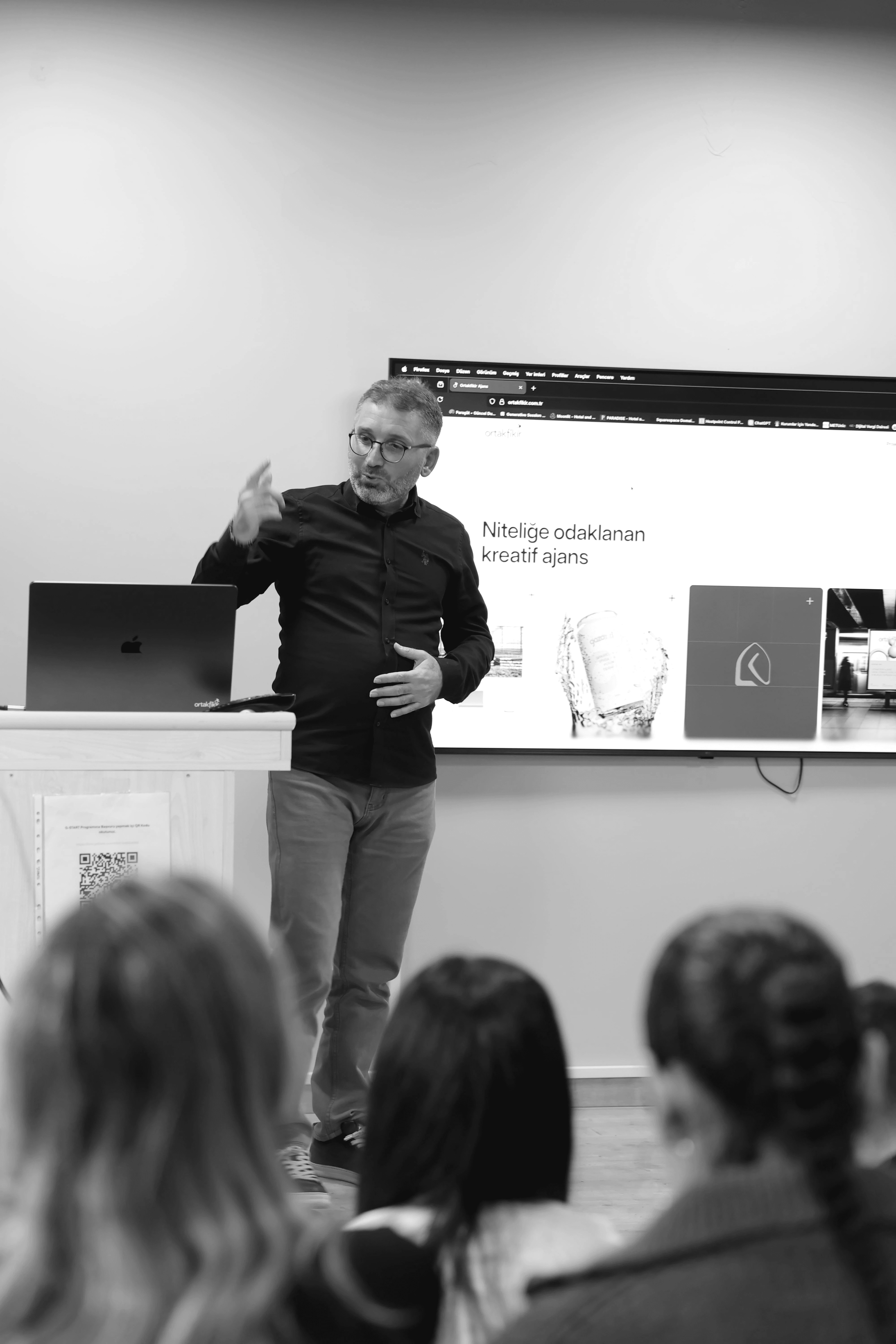 Four people engage in conversation in front of a wall with text, all smiling and interacting in a casual setting.