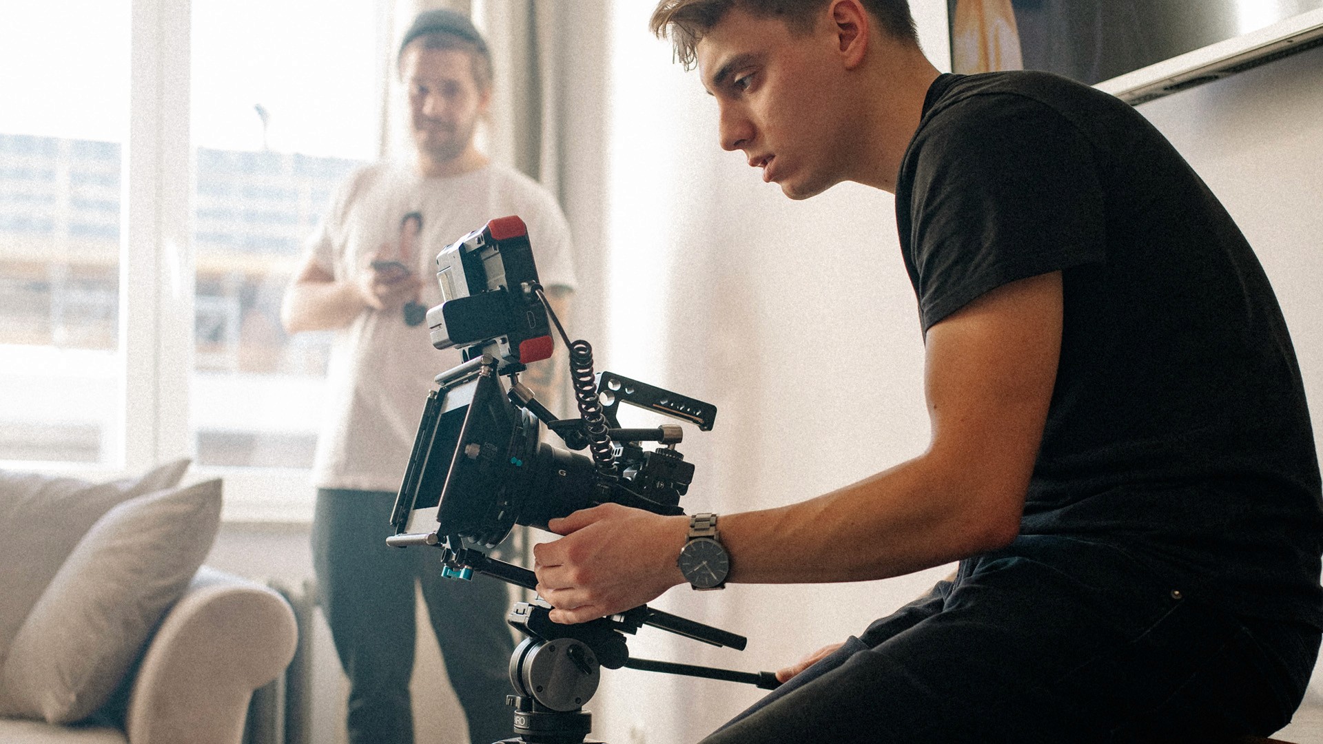 A thoughtful young person with dark hair gazes to the side, captured in soft black and white lighting.