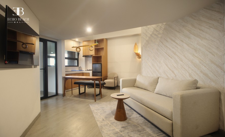 Living and kitchen area of the Mezzanine apartment suite at Echo Beach, Canggu, Bali, with a large sofa and stylish wall textures.