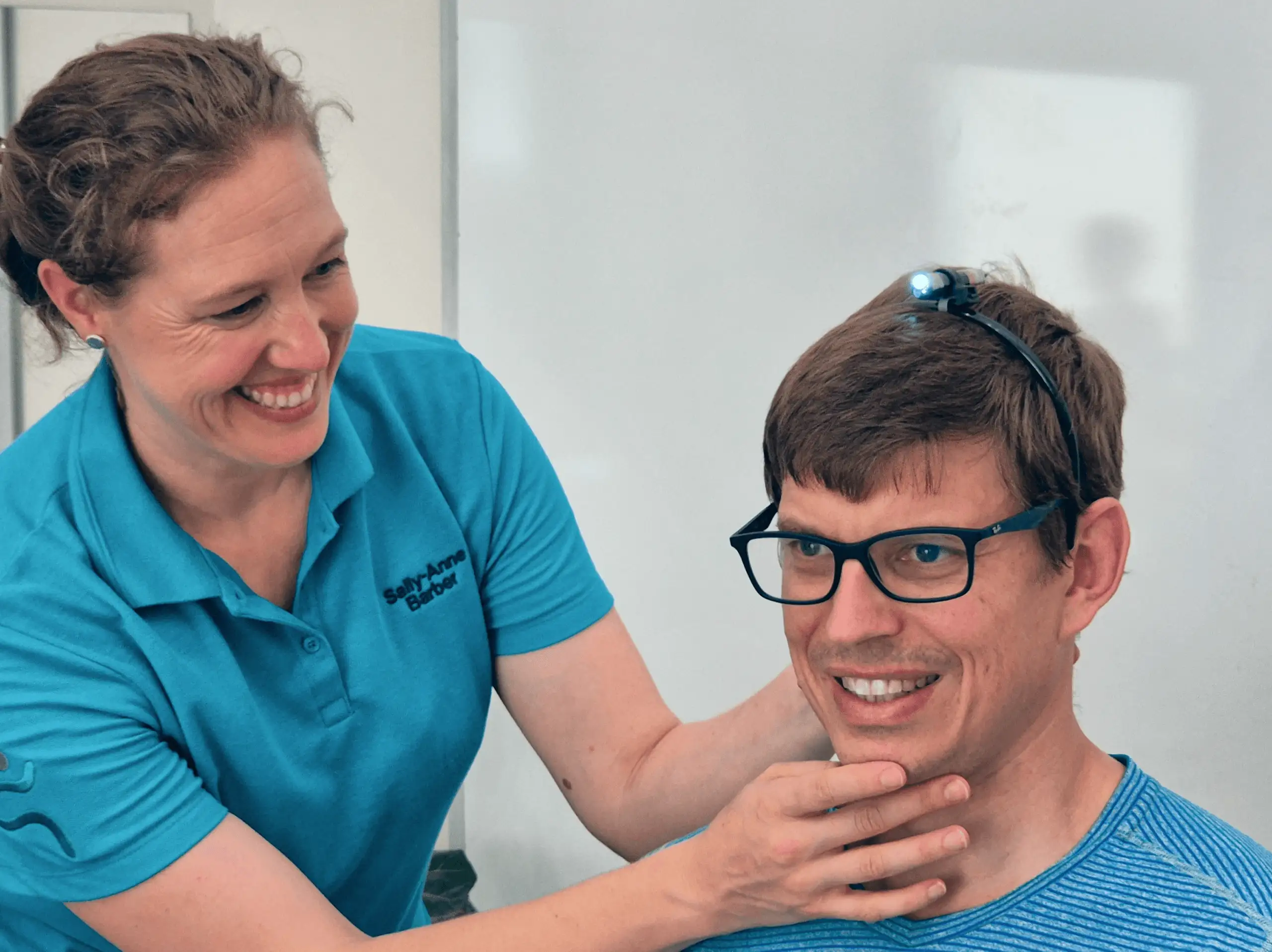 A Physiotherapist tests neutral neck position of a client by adjusting the chin of a male patient