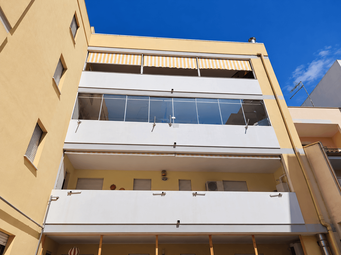 Vista esterna del condominio con balcone chiuso tramite vetrata panoramica.