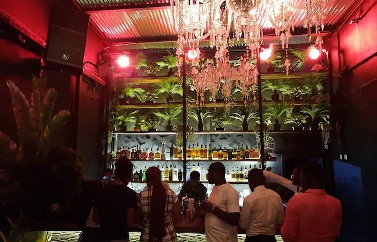 Guests enjoying drinks in a lively bar with a warm red glow during a BookAfrica experience.