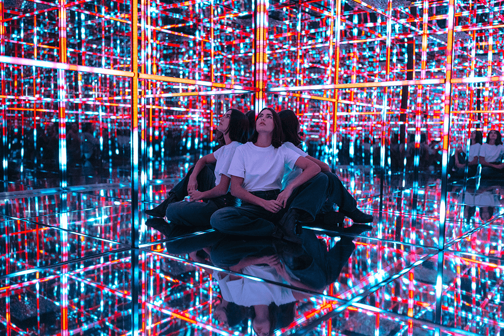 Dziewczyna zafascynowana kolorowymi odbiciami w lustrach na wystawie w Melt Museum, gdzie innowacyjny platforma do sprzedaży biletów Going. Places ułatwia integrację zakupów i rezerwacji z estetyką wydarzenia