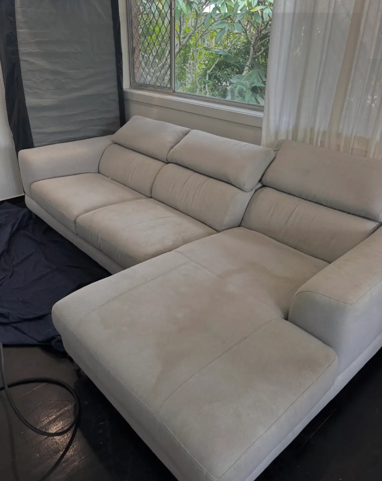Light grey sectional sofa with visible dark water spots and stains on the cushions before a professional furniture deep clean.