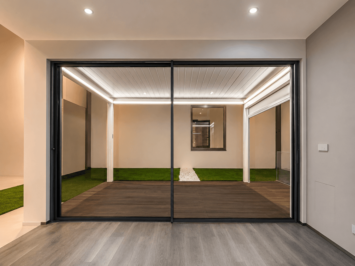 Grande vetrata scorrevole in alluminio dal design minimale installata in ambiente moderno contemporaneo. Serramento panoramico Fortezza con profili sottili, ampia superficie vetrata e continuità tra interno ed esterno.