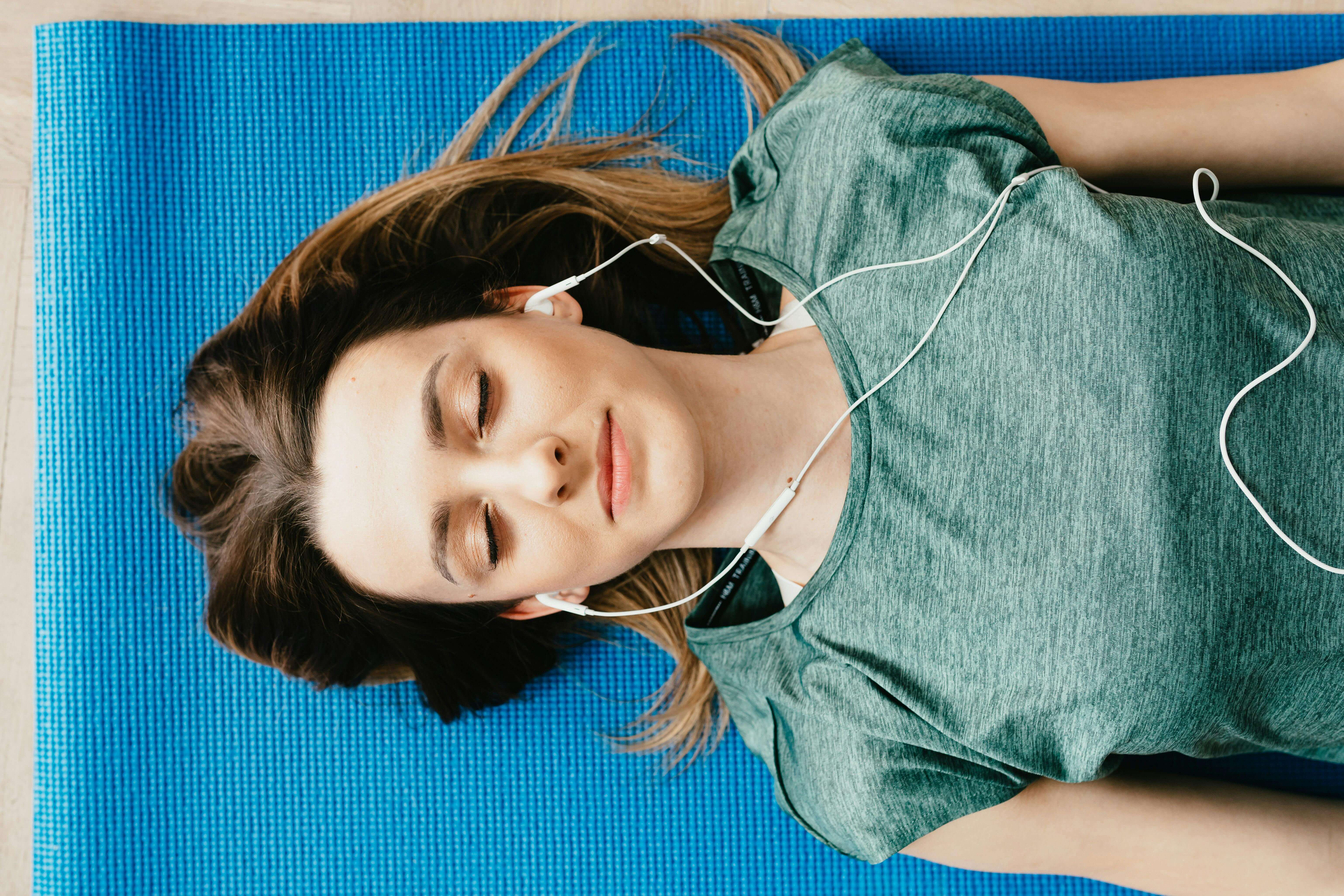 une image d'une femme allongé les yeux fermés, écoutant de la musique