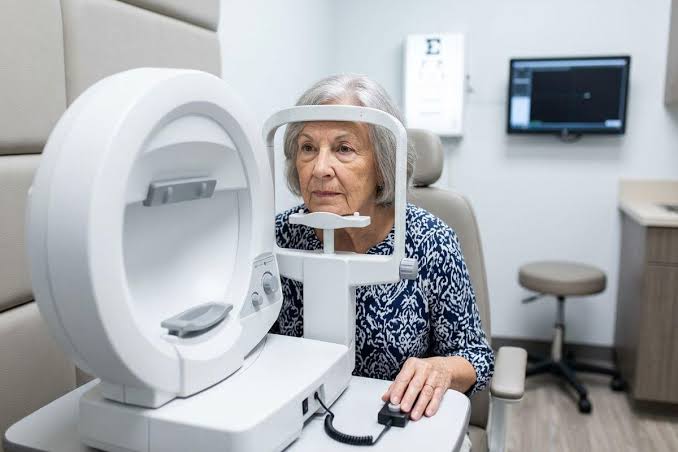 older woman having an eye test at an optometrist, chin on the machine rest