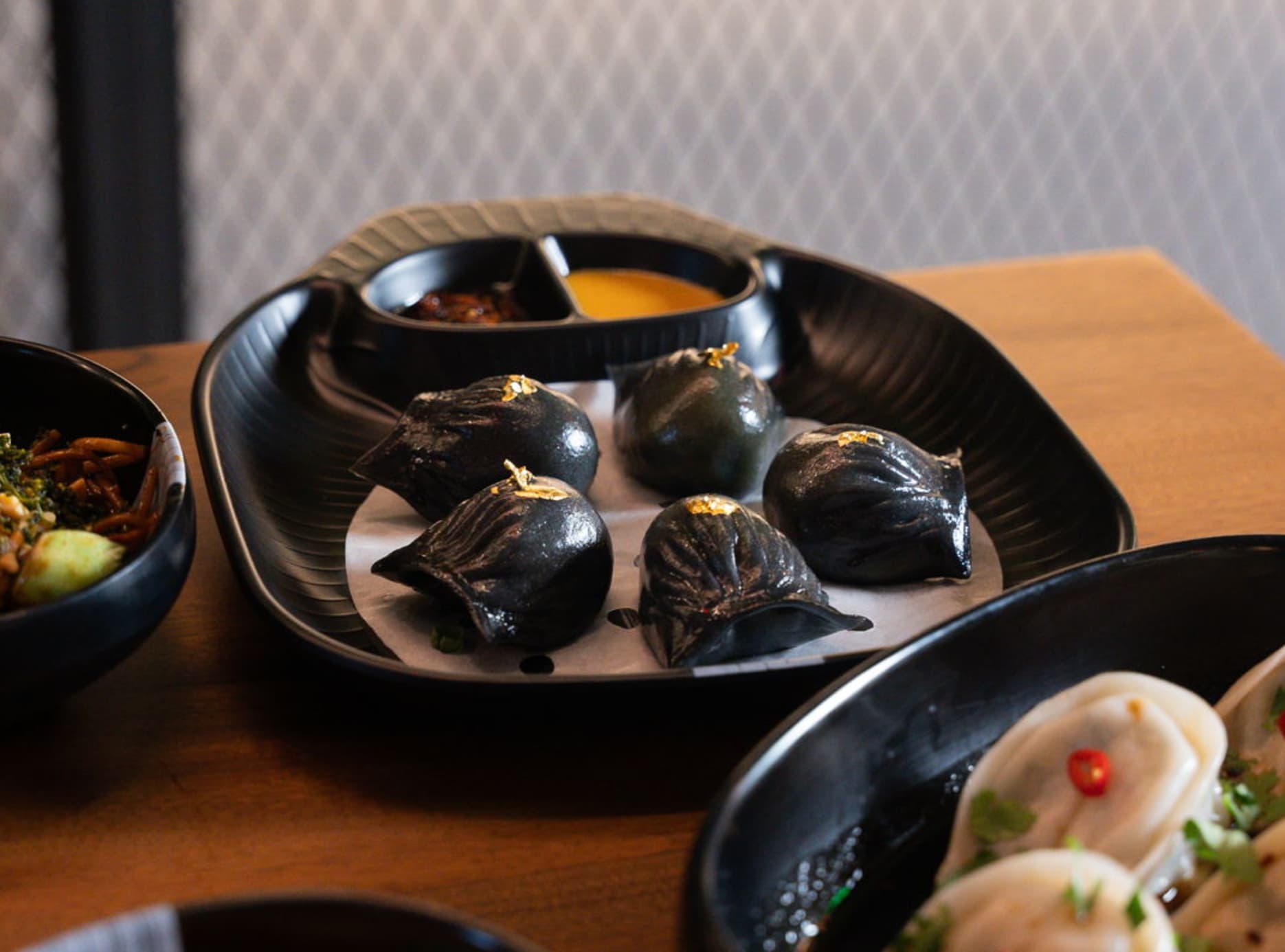 Vegan food, activated goldsum charcoal dumplings filled with edamame and water chestnut, finished with truffle oil and edible gold