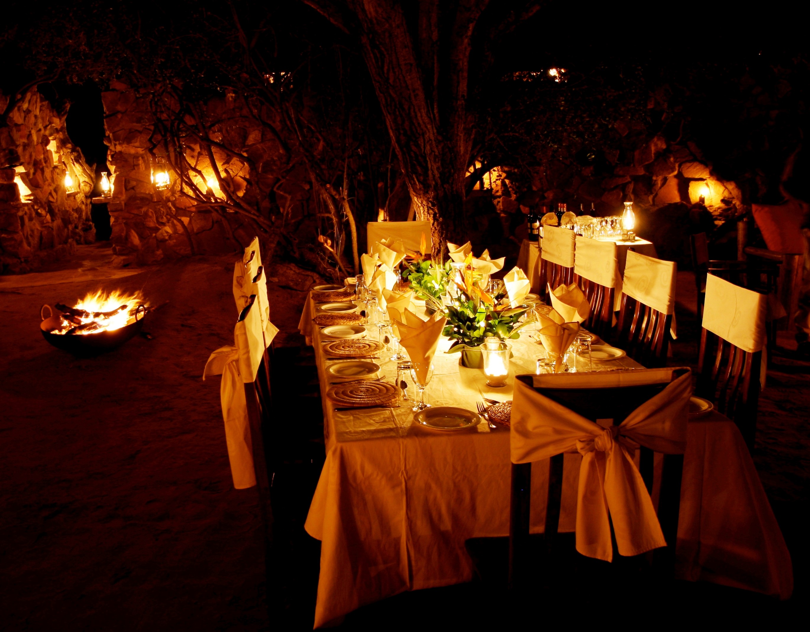 Grupp av ryttare på ridresa i Afrika galopperar över Serengetis vidsträckta slätter medan damm och gnuhjordar rör sig över horisonten under the great migration.