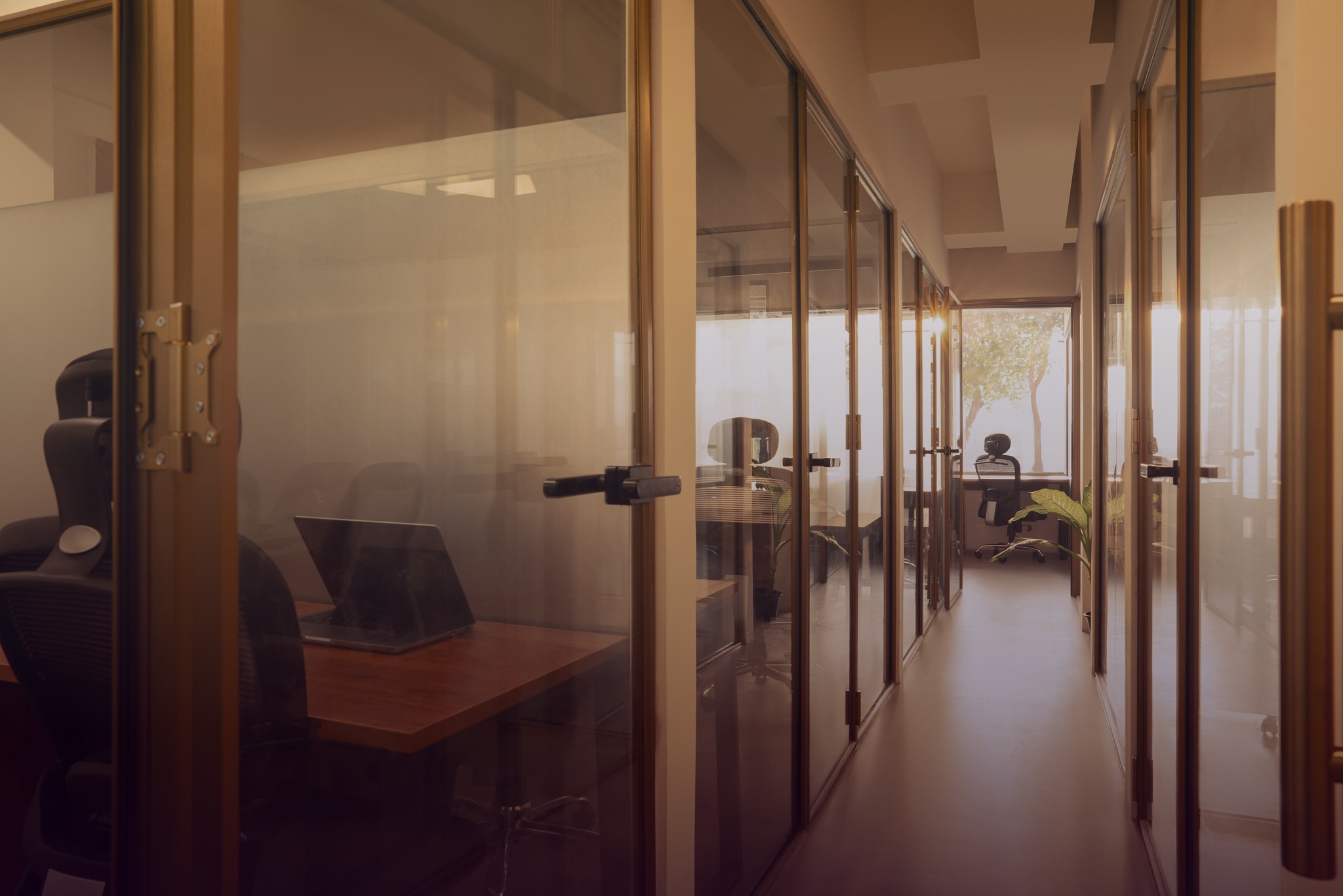 A softly lit hallway with a series of arched doorways, warm-toned walls, and wood flooring leading toward a seating area with neutral furniture.
