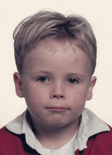 A woman with long blonde hair, in a brown top and jeans, walks through a sunlit forest, holding someone's hand. The scene is warm and inviting.
