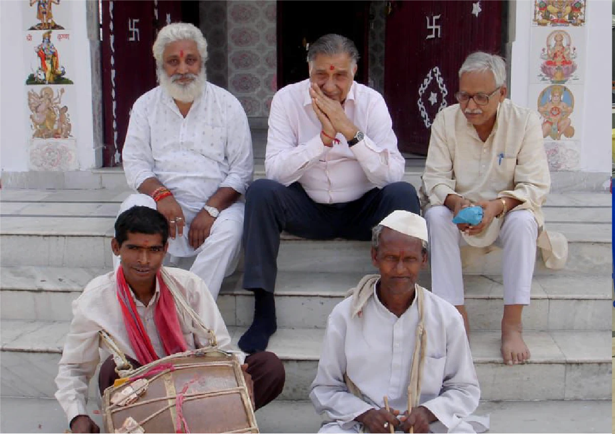 Shri Lalit Prasad Naithani sitting with his friends on the steps of a building.