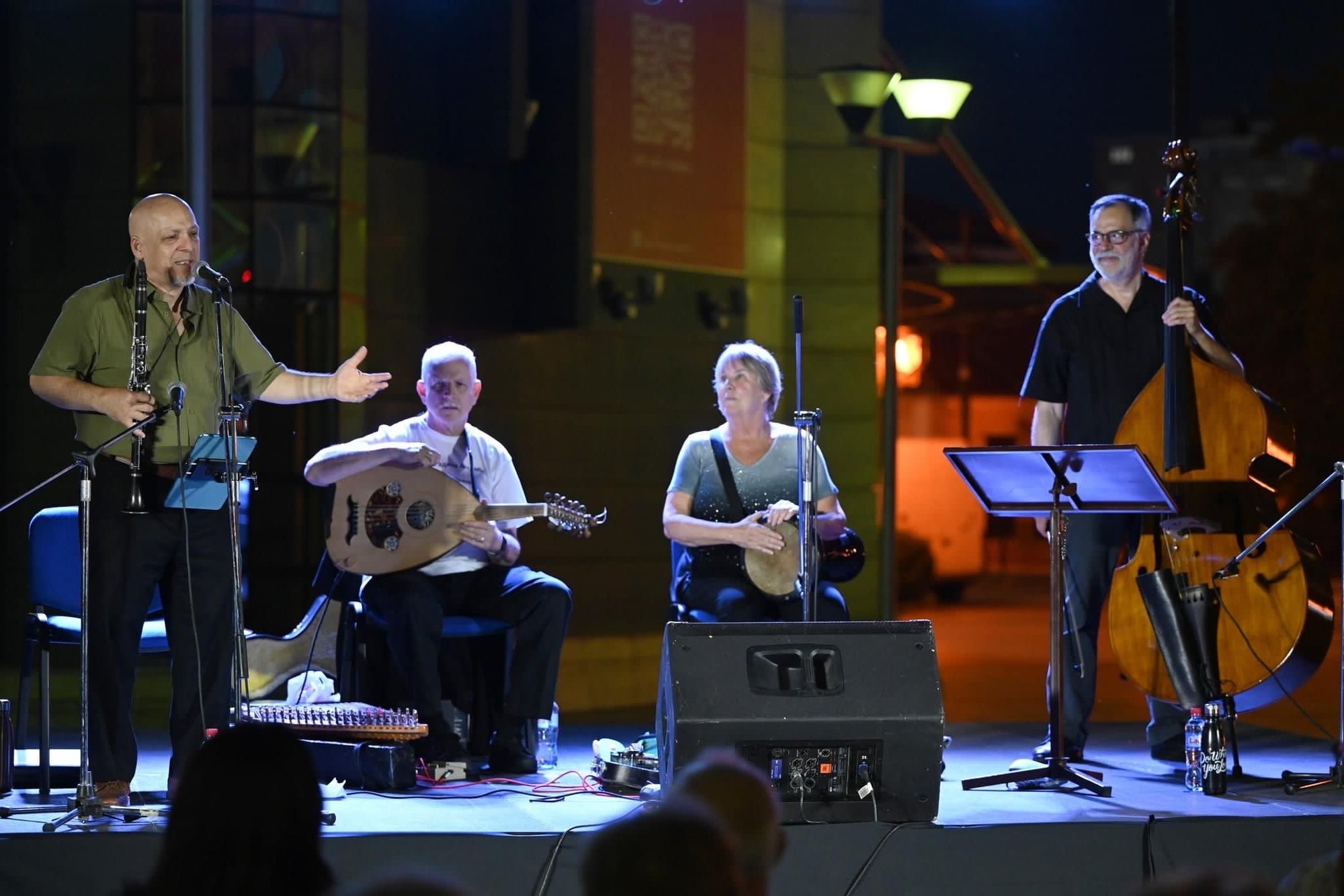 The ensemble on an outdoor stage at night, Daniel Elias at the microphone