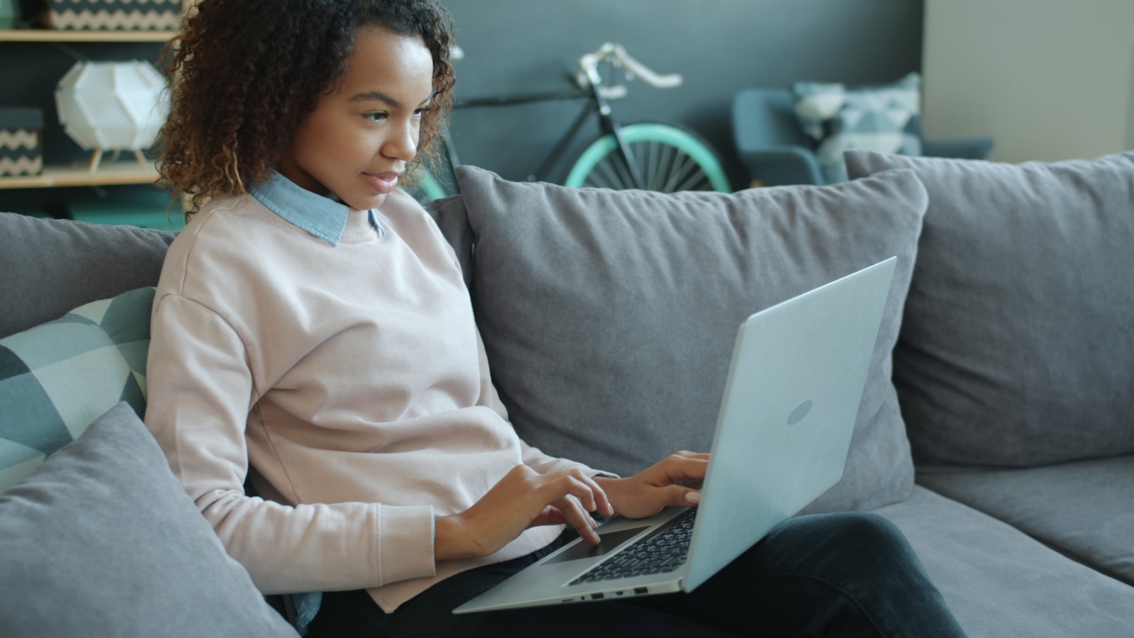 A woman sitting on a couch using a laptop at home for a virtual telehealth nutrition appointment