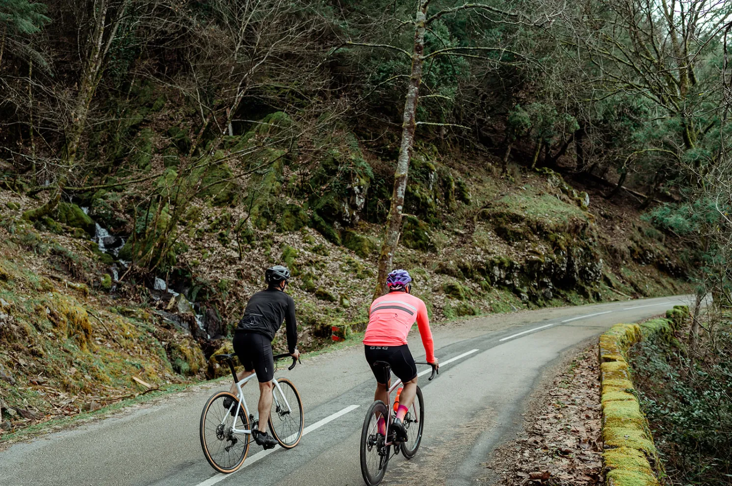 Two people riding their bikes on a road.